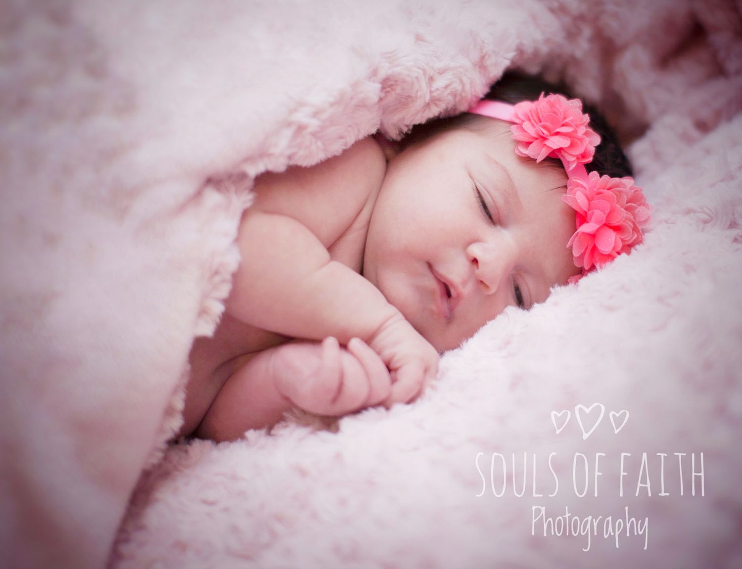 Newborn baby girl sleeping peacefully wrapped in soft pink blanket with pink flower headband, Souls of Faith Photography.