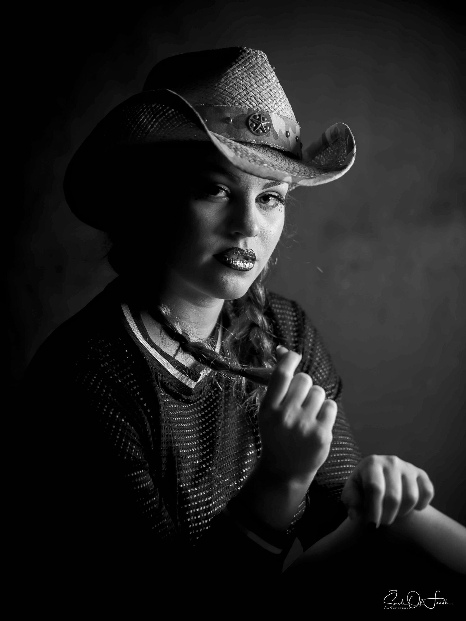 Black and white portrait of a young woman wearing a cowboy hat, holding a pipe in a dramatic studio setting.SATX ATX HTX DFW Austin San Anto