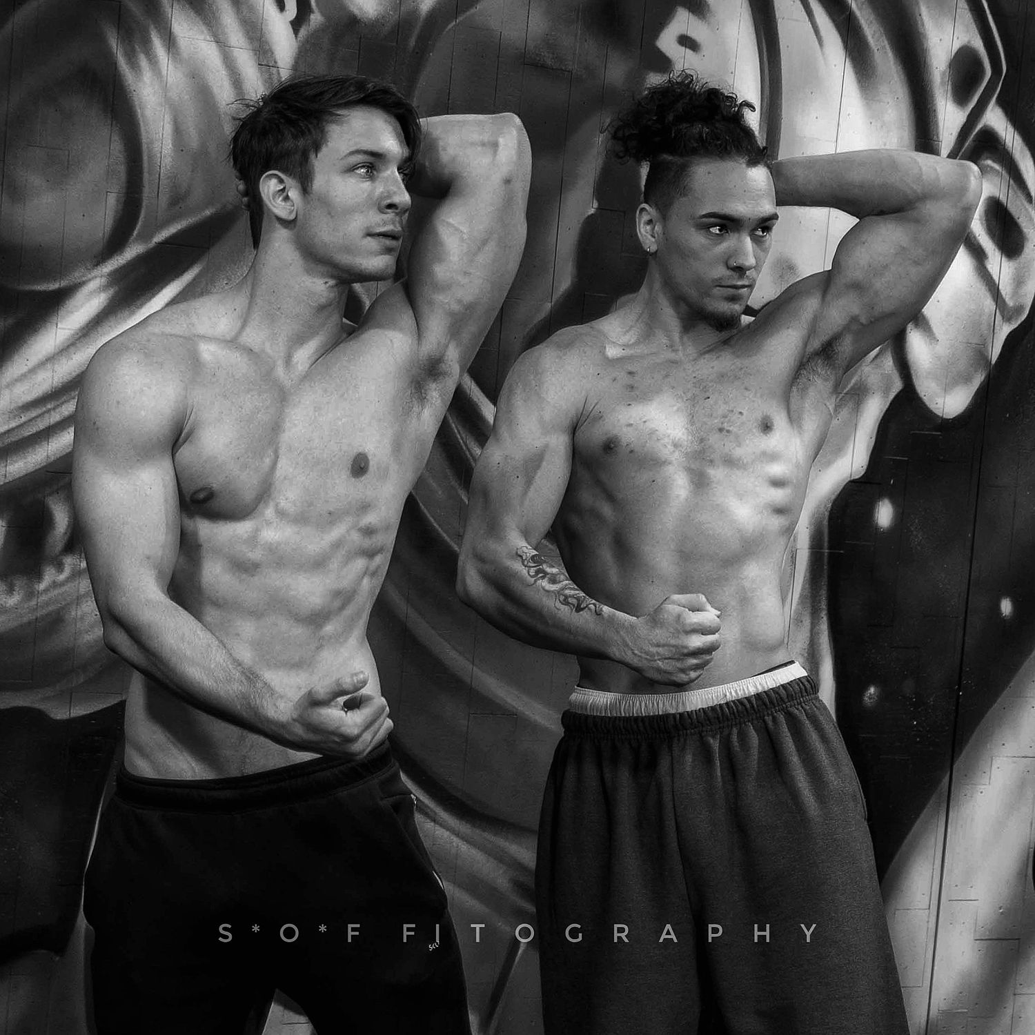 Two muscular shirtless men pose confidently in a black and white fitness photography shot by S*O*F Fitography.