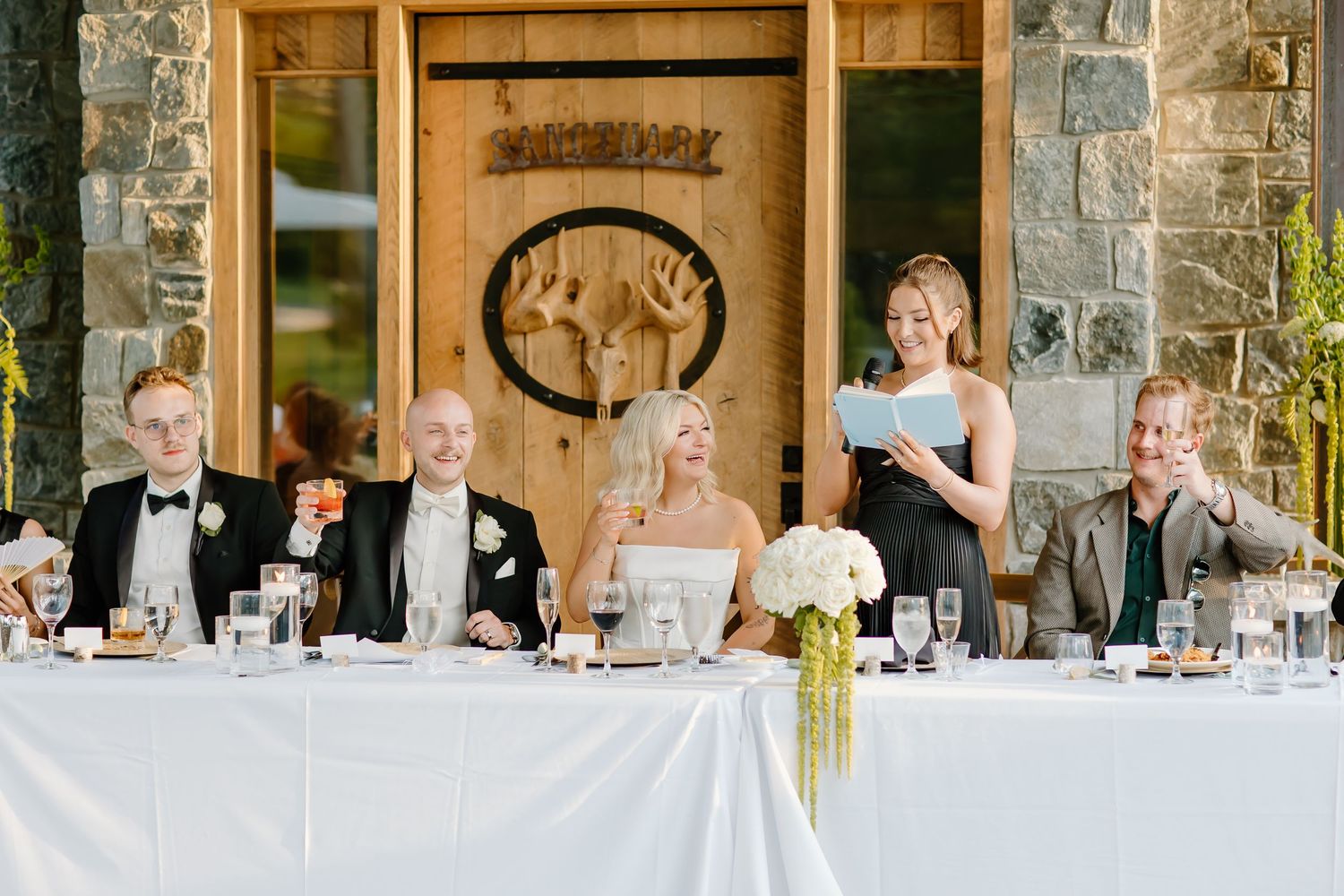 Wedding reception in rustic stone venue with long tables and elegant white decor.