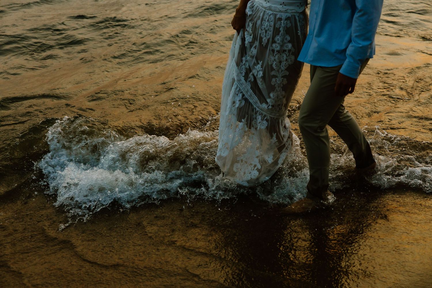 Legs splashing in shallow beach water during golden hour.