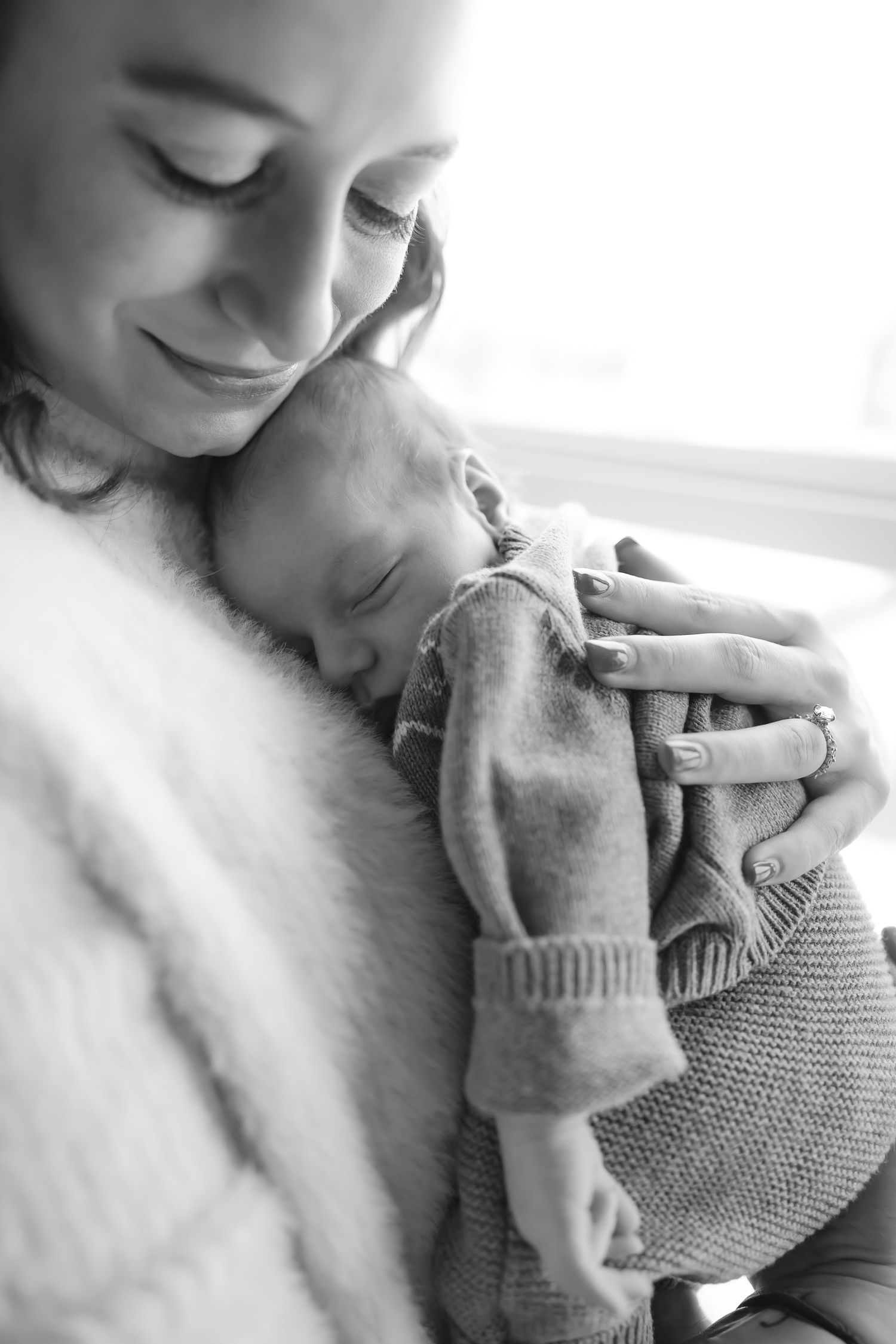 Close-up of tender moments with a newborn baby wrapped in a gray knit blanket.