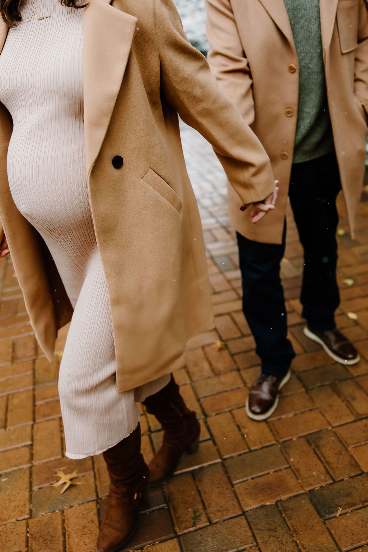 Detail shots of winter maternity fashion with camel coat and cream dress on brick path.