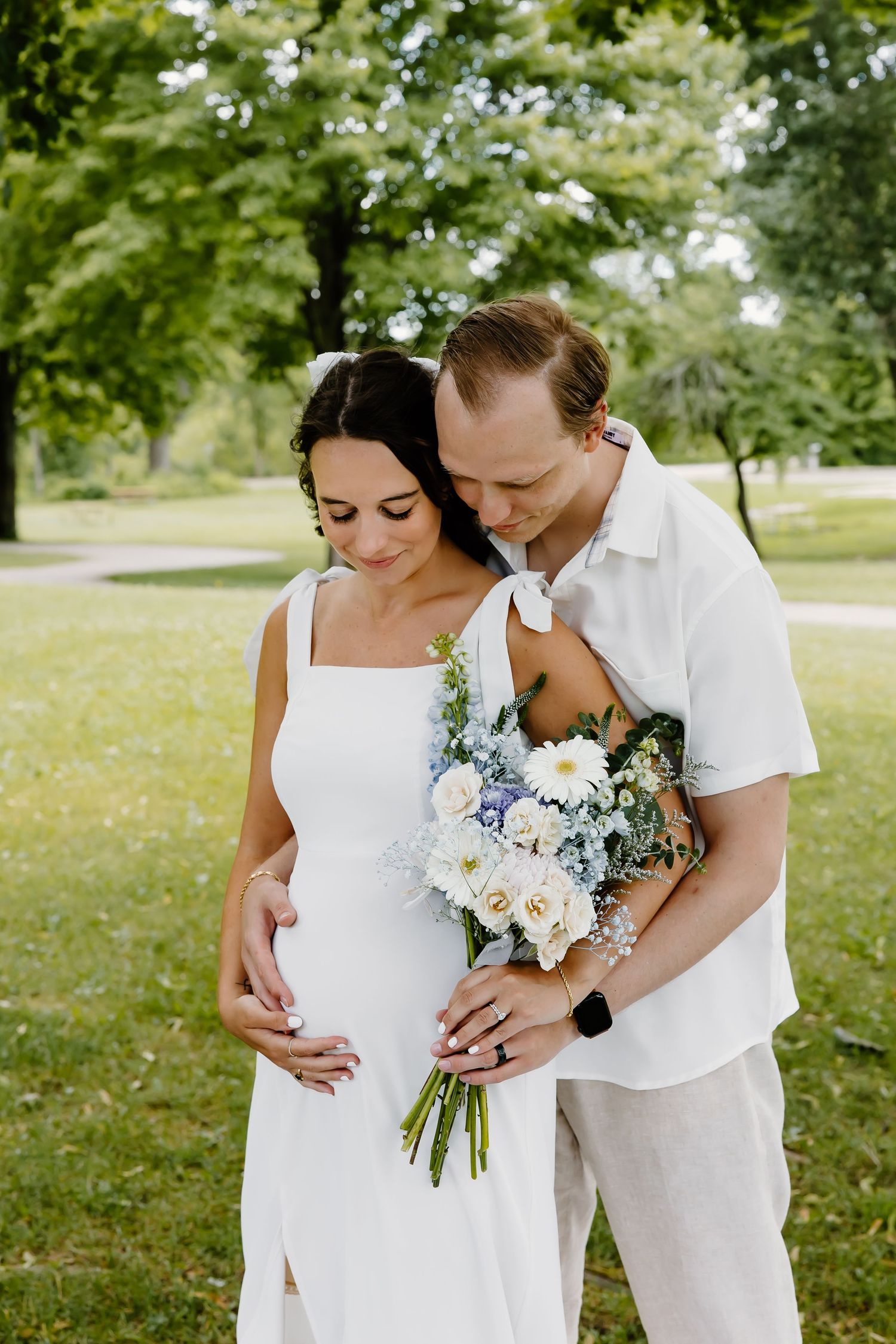 Sweet pregnancy announcement photoshoot in a sunny park setting.