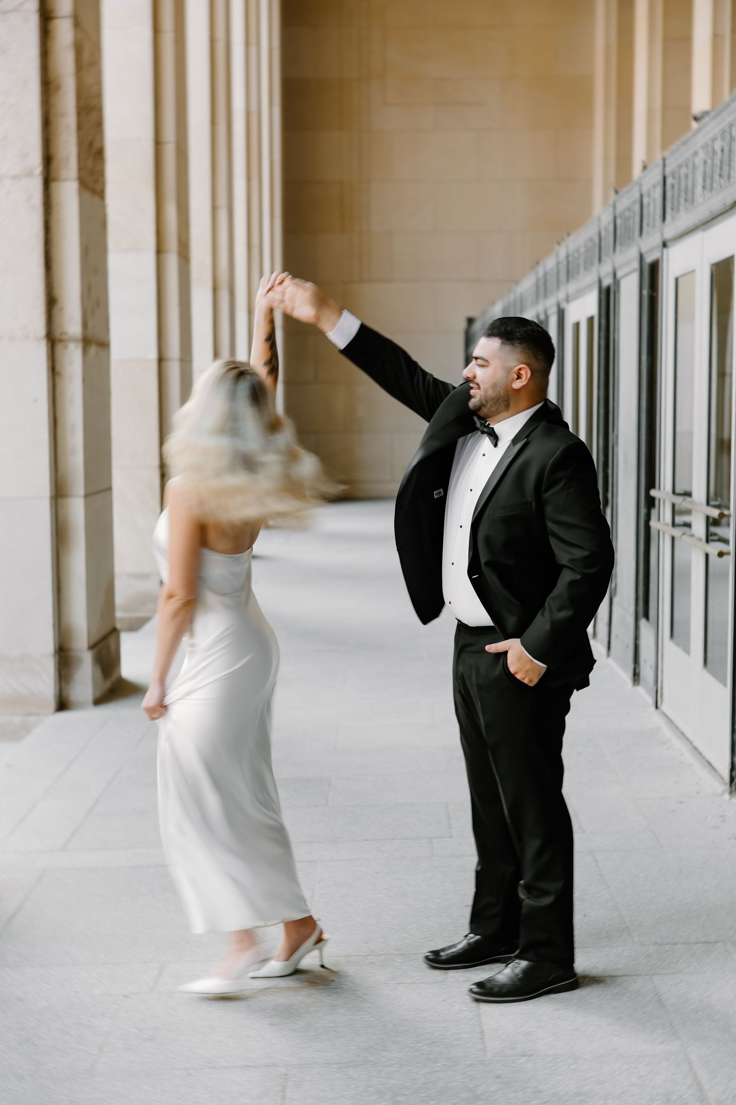 Dancing couple in formal wear spins in elegant hallway.