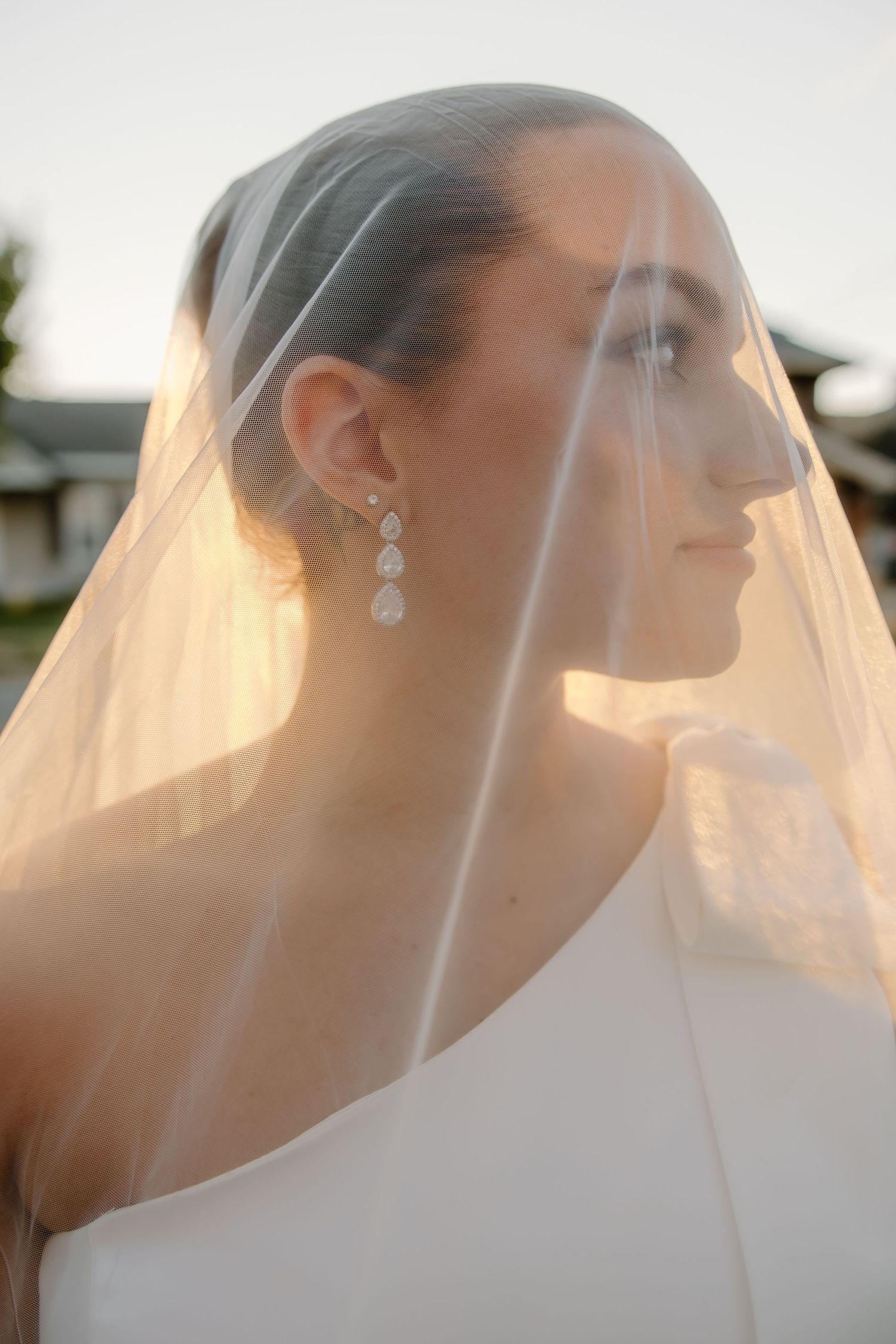 A delicate wedding veil catches the golden sunlight creating a dreamy silhouette.