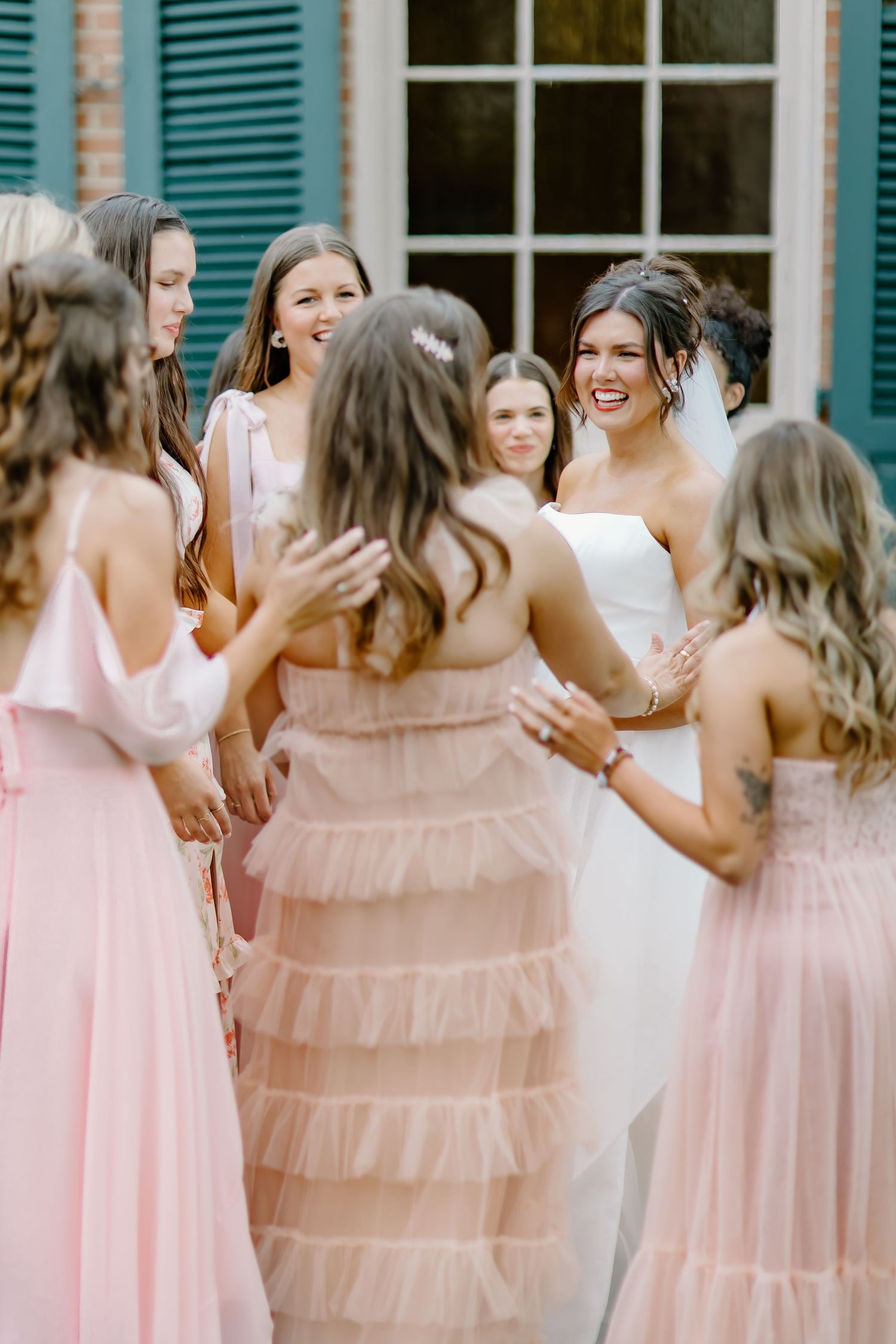 Joyful wedding party moment with bridesmaids in pink dresses sharing laughter.