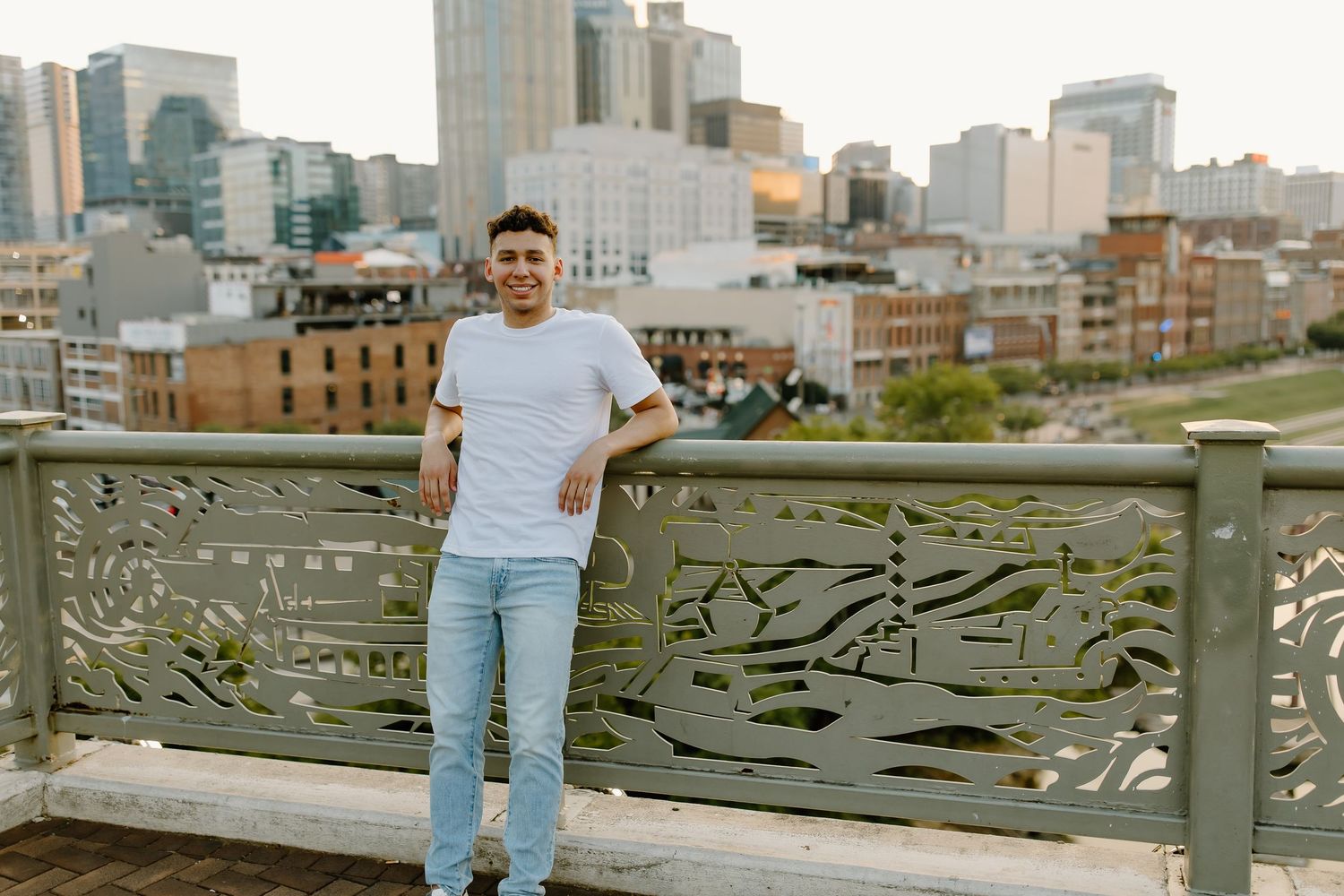 Person sitting on a stone wall overlooking a cityscape with tall buildings in the background.