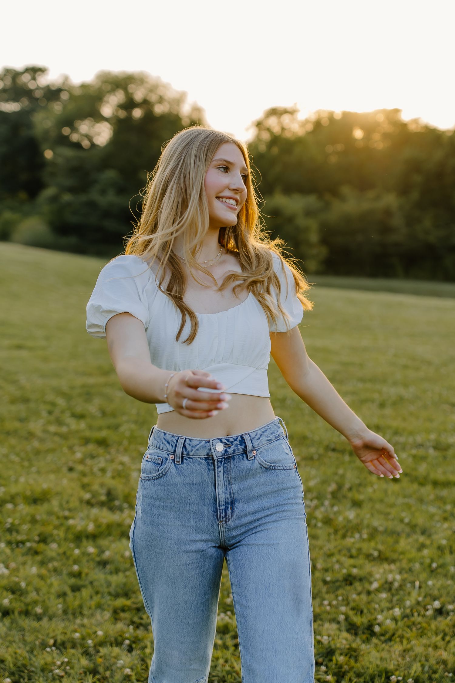 Someone in casual attire enjoying a carefree moment in a grassy field.