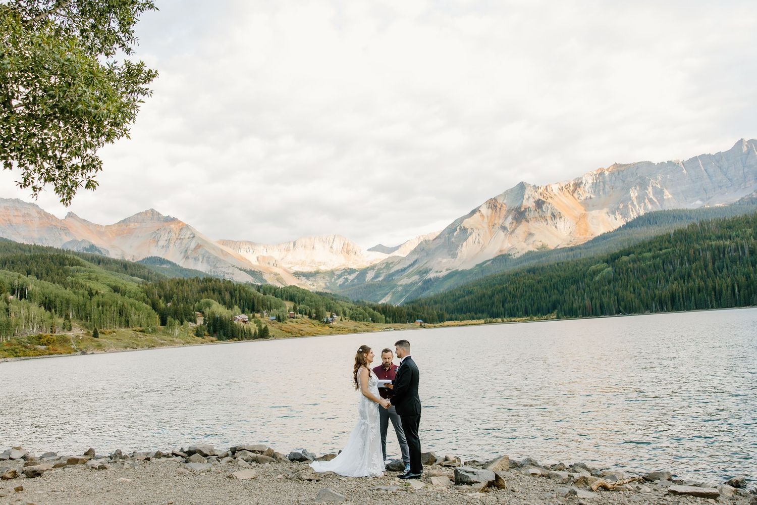 Scenic mountain wedding venue with lake and forest views under cloudy skies.