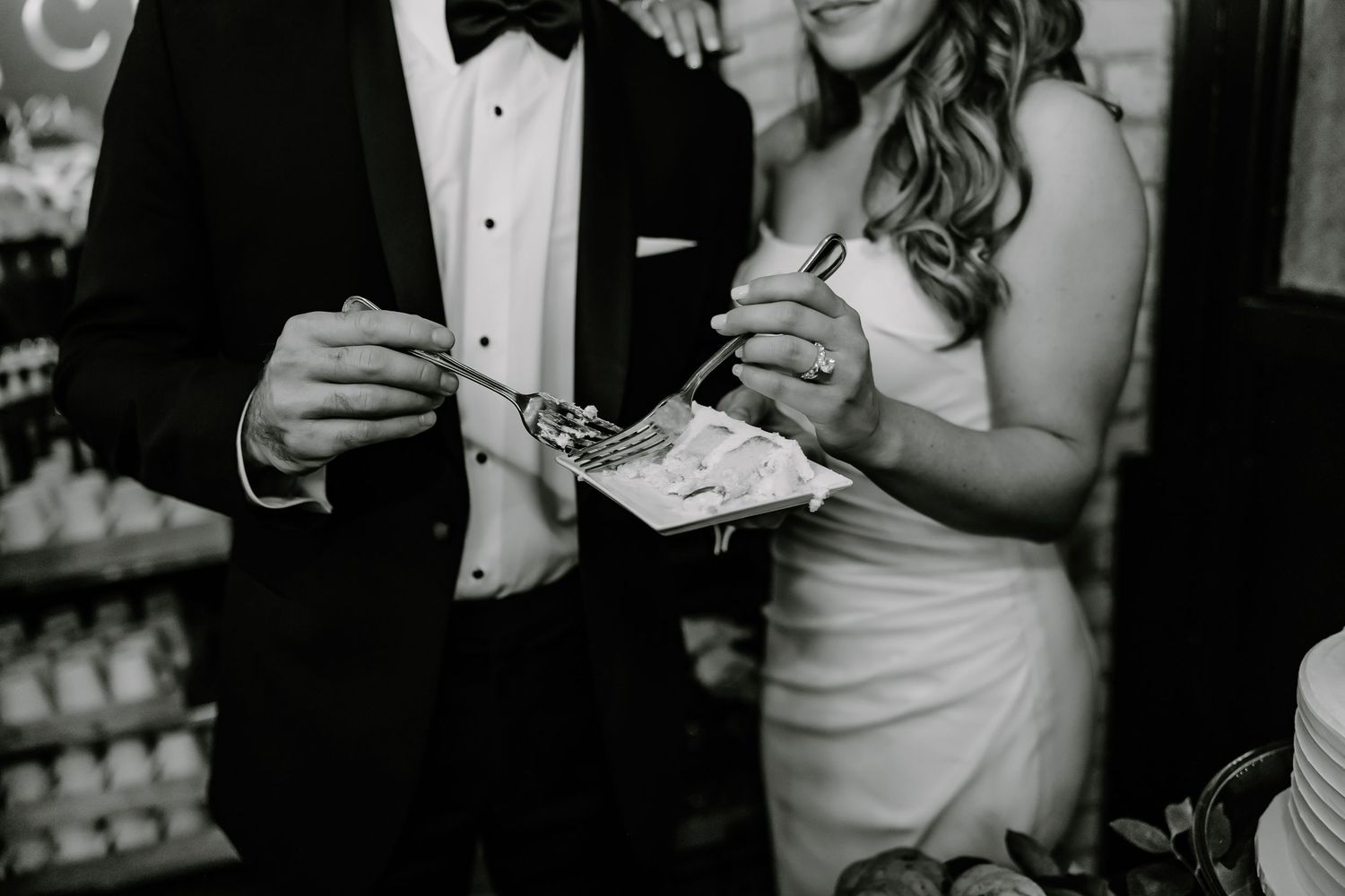 Black and white photo of wedding cake cutting moment at reception.