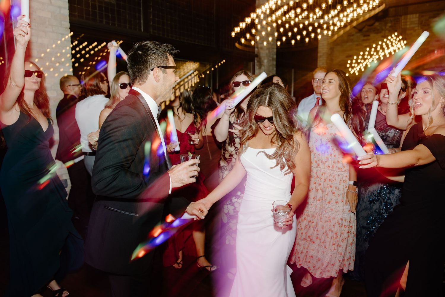 Wedding reception dance floor filled with guests under string lights.