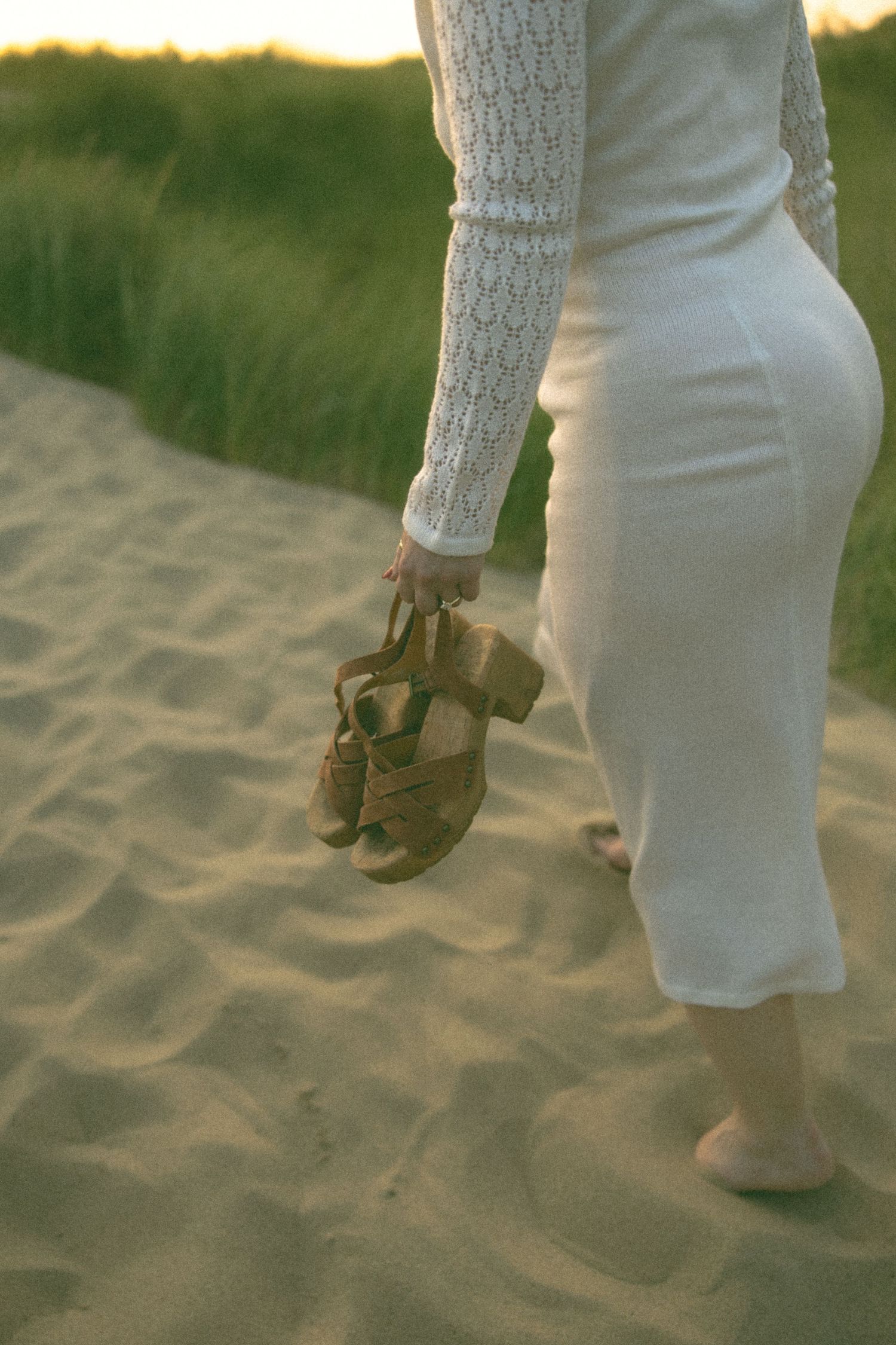 Close-up of footprints in beach sand during a sunset photoshoot.