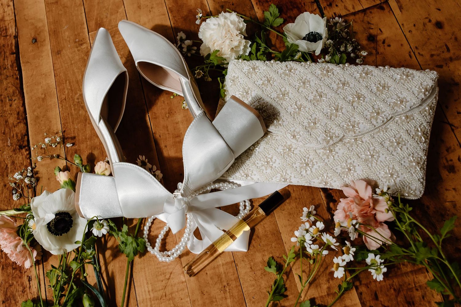 Wedding accessories and floral elements artfully arranged on a rustic wooden surface.