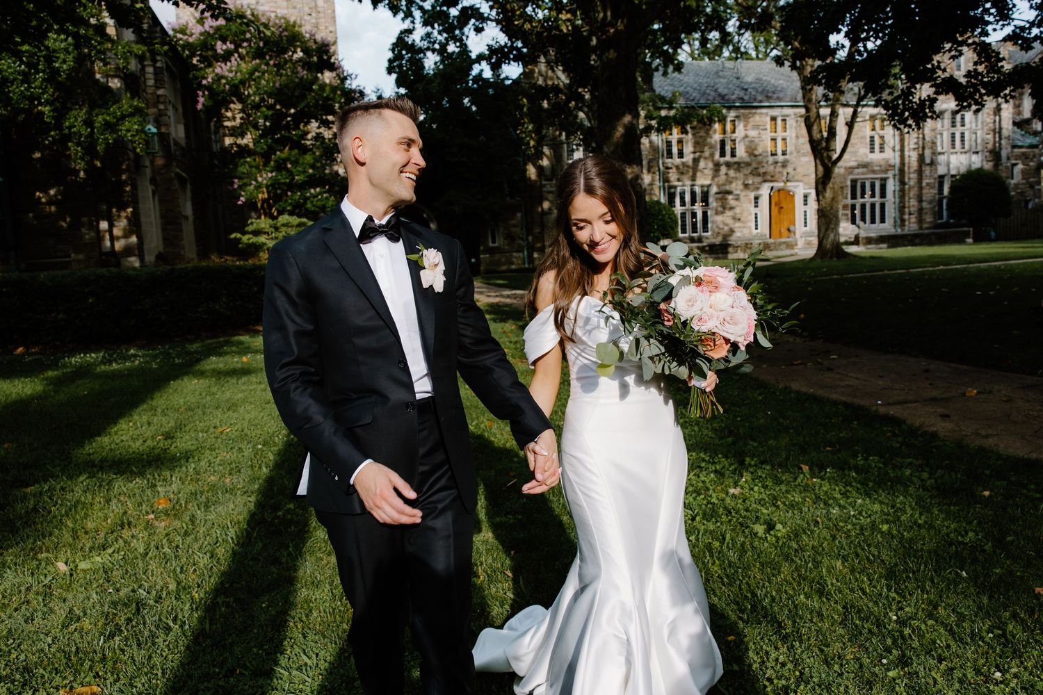 Sunny outdoor wedding photos on green lawn near historic church building.
