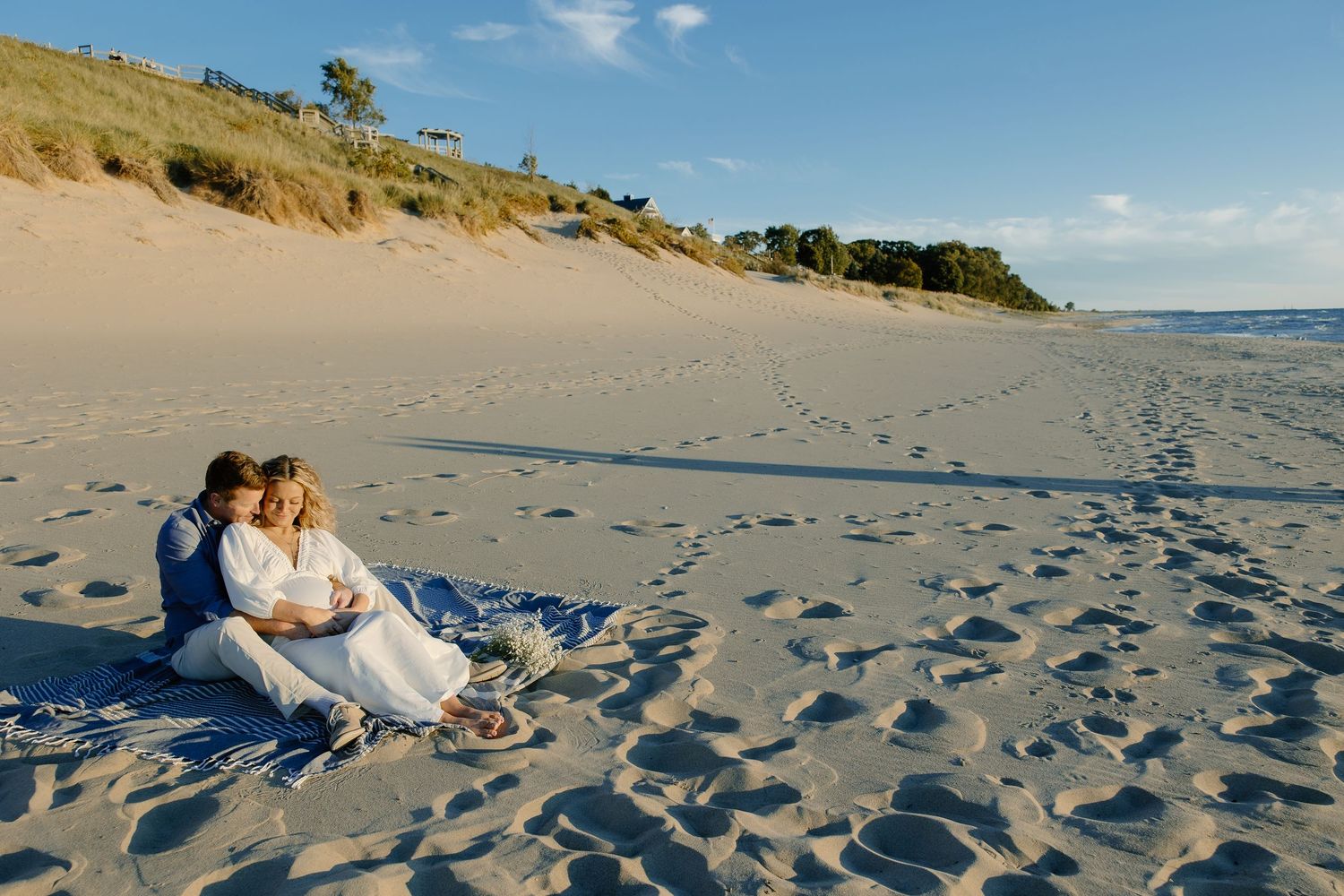 Scenic beach landscape with sand dunes and couple enjoying golden hour.