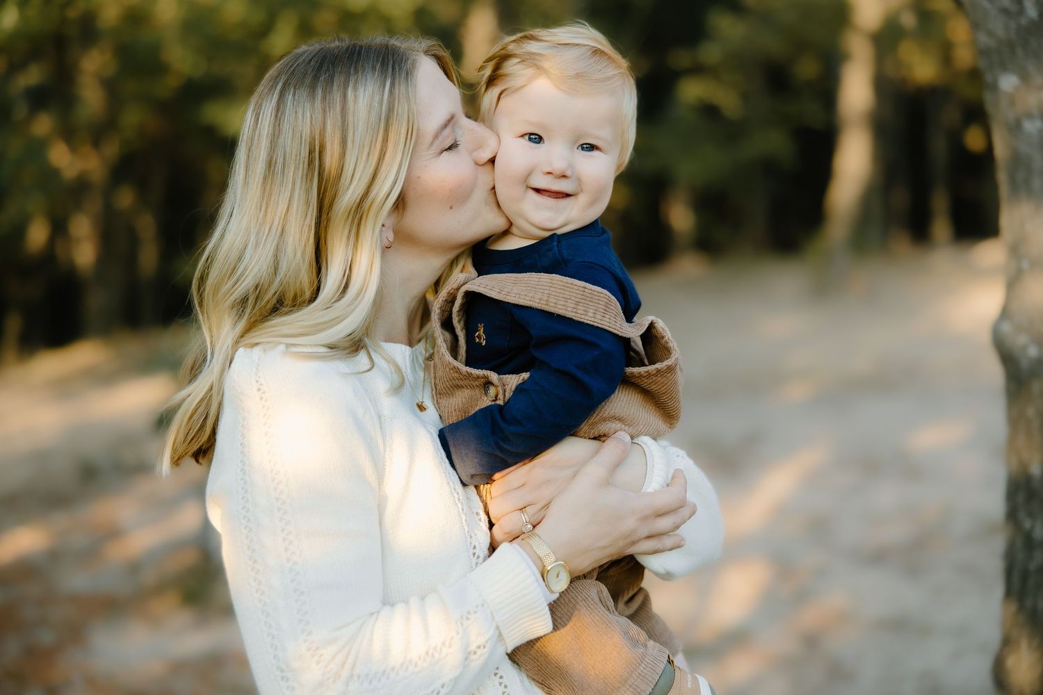 A loving family moment captured in warm sunlight during an outdoor autumn photoshoot.