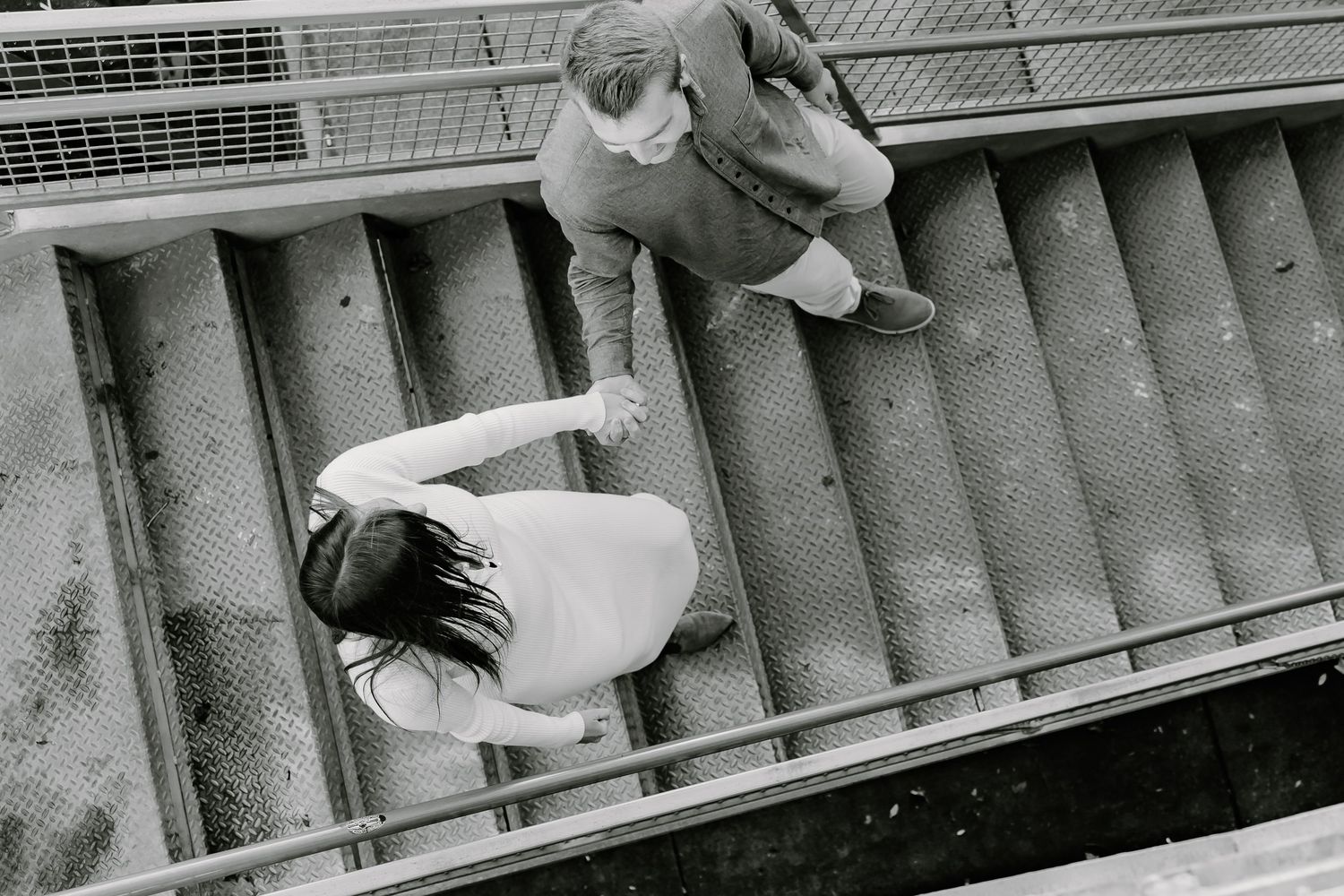 Two people walking down concrete steps in a dramatic black and white composition.