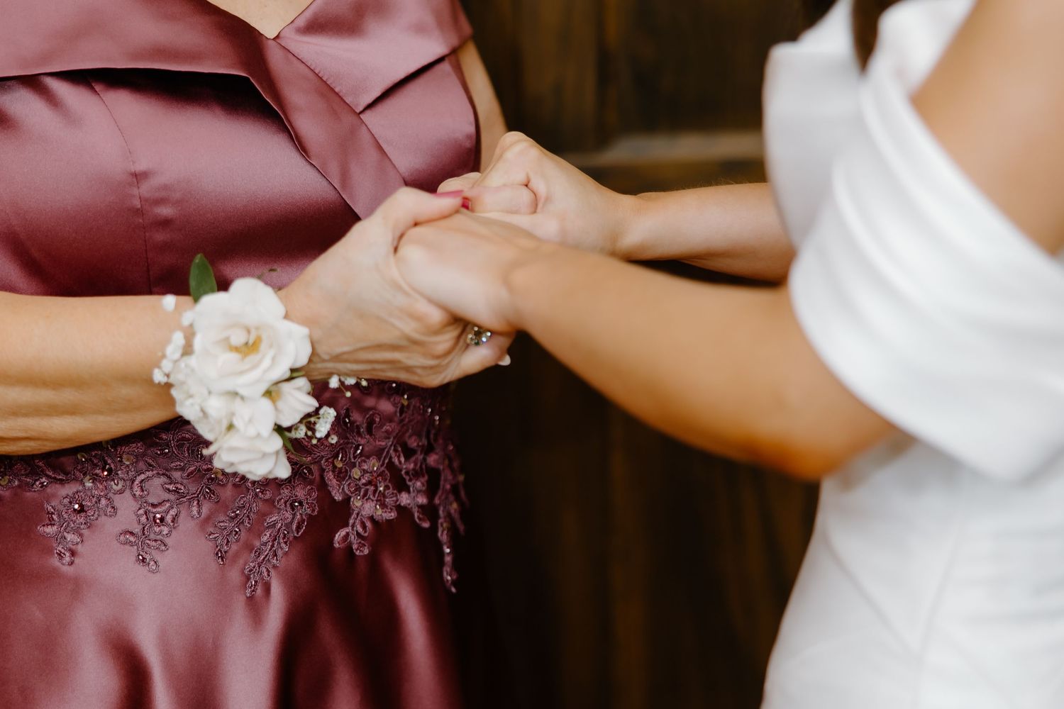 Close-up details of burgundy bridesmaid dresses with white floral accents.