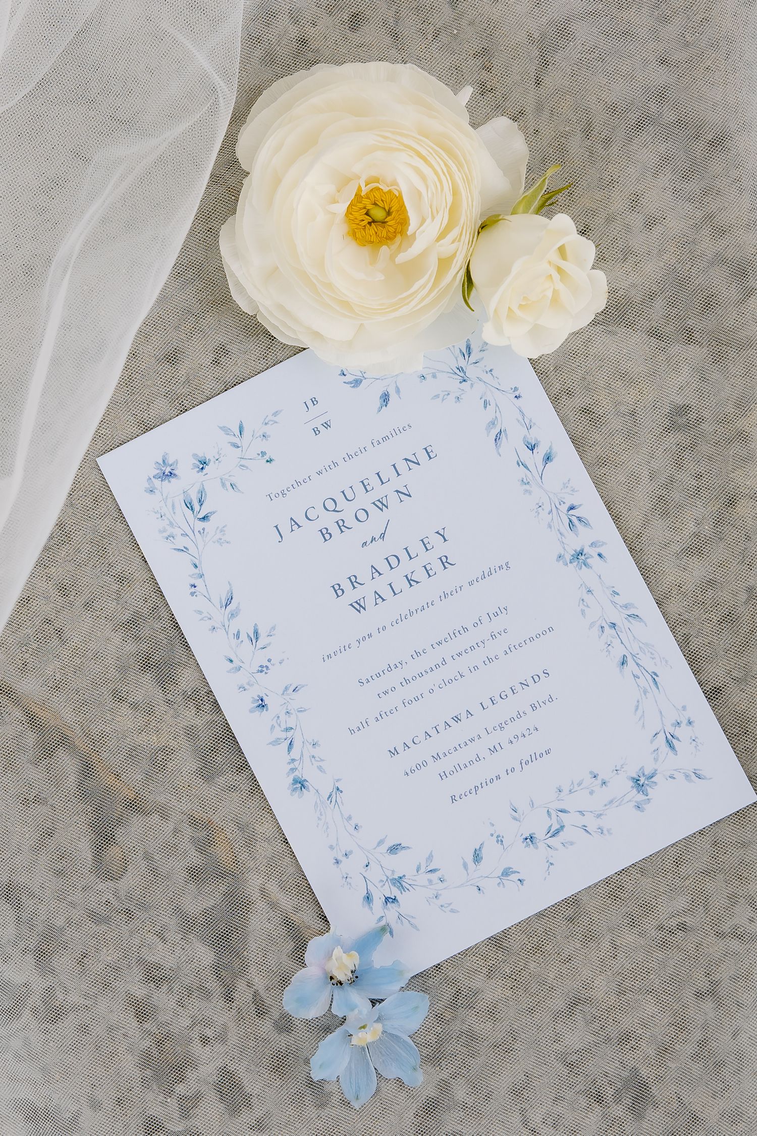 Wedding invitation with delicate blue floral design and white roses on concrete background.