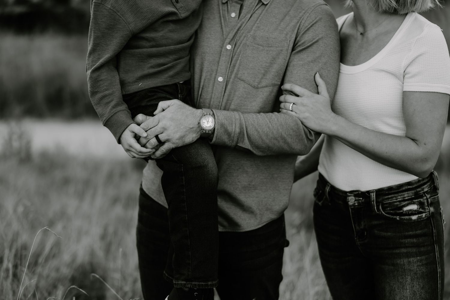Black and white cropped photo showing couple holding hands during outdoor engagement photoshoot session.