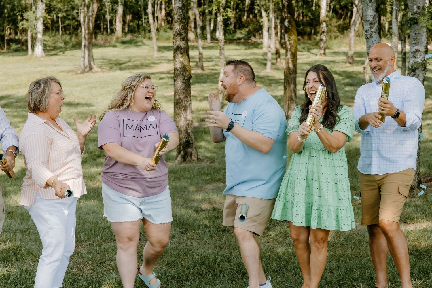 Family and friends gathered outdoors for a gender reveal party celebration.