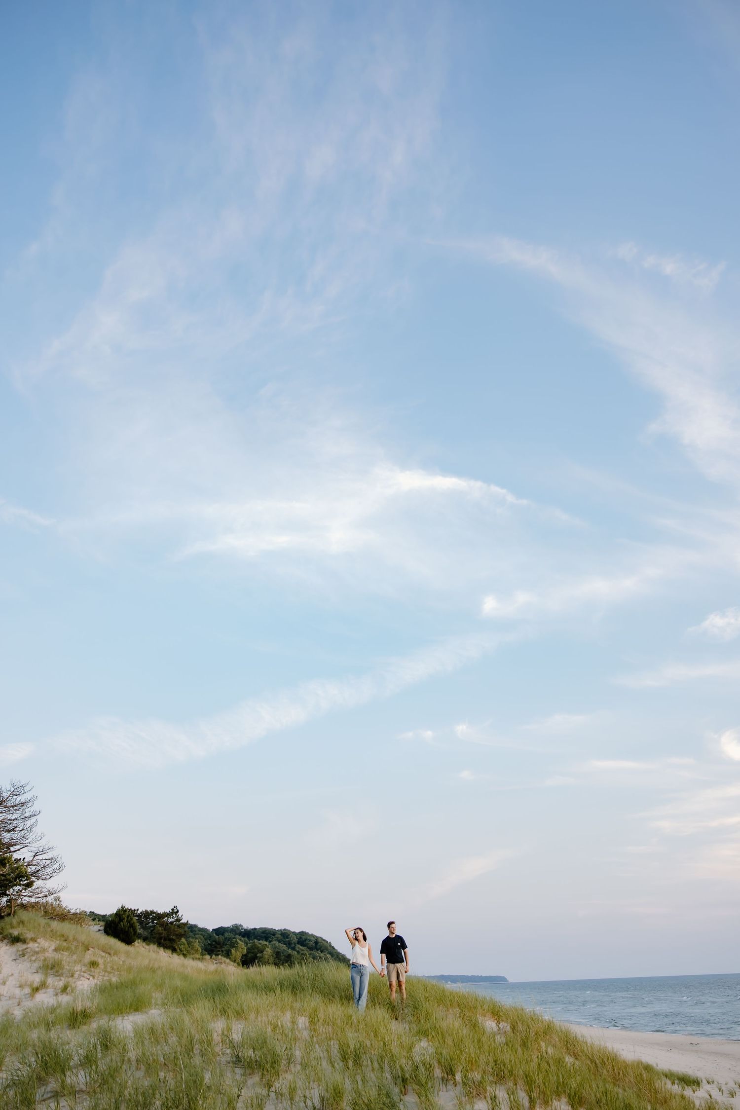 Scenic coastal landscape with sand dunes, beach grass, and blue sky over Lake Michigan.