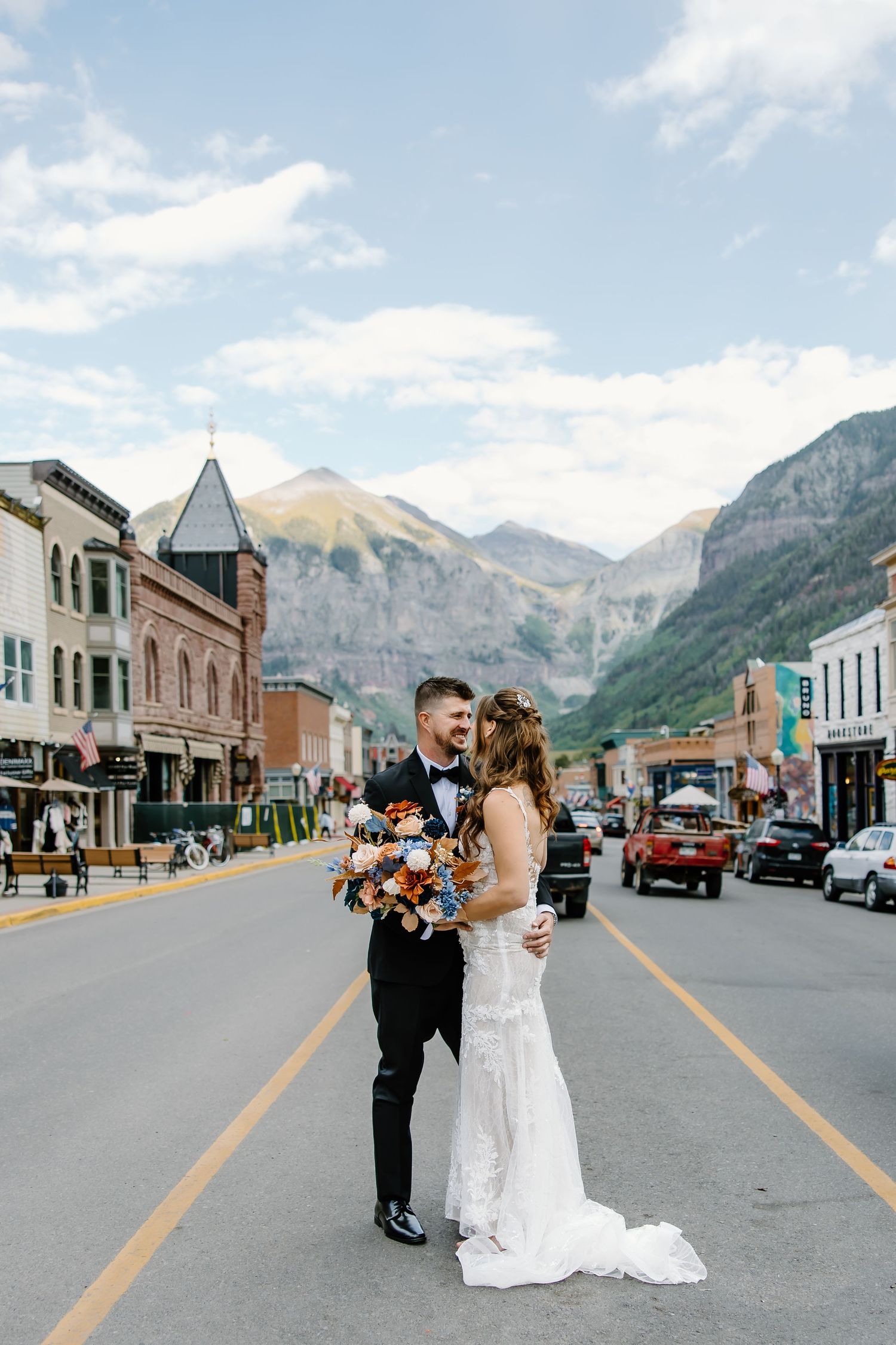 Newlyweds pose in the middle of a charming mountain town's historic main street.