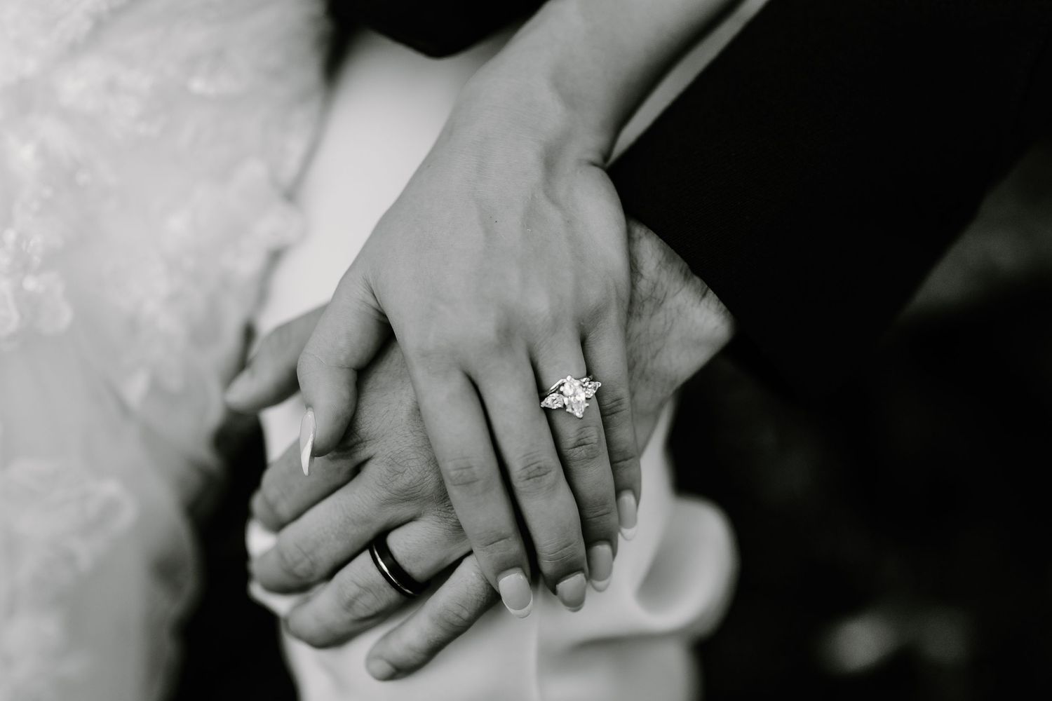 Black and white close-up of hands with wedding rings intertwined.
