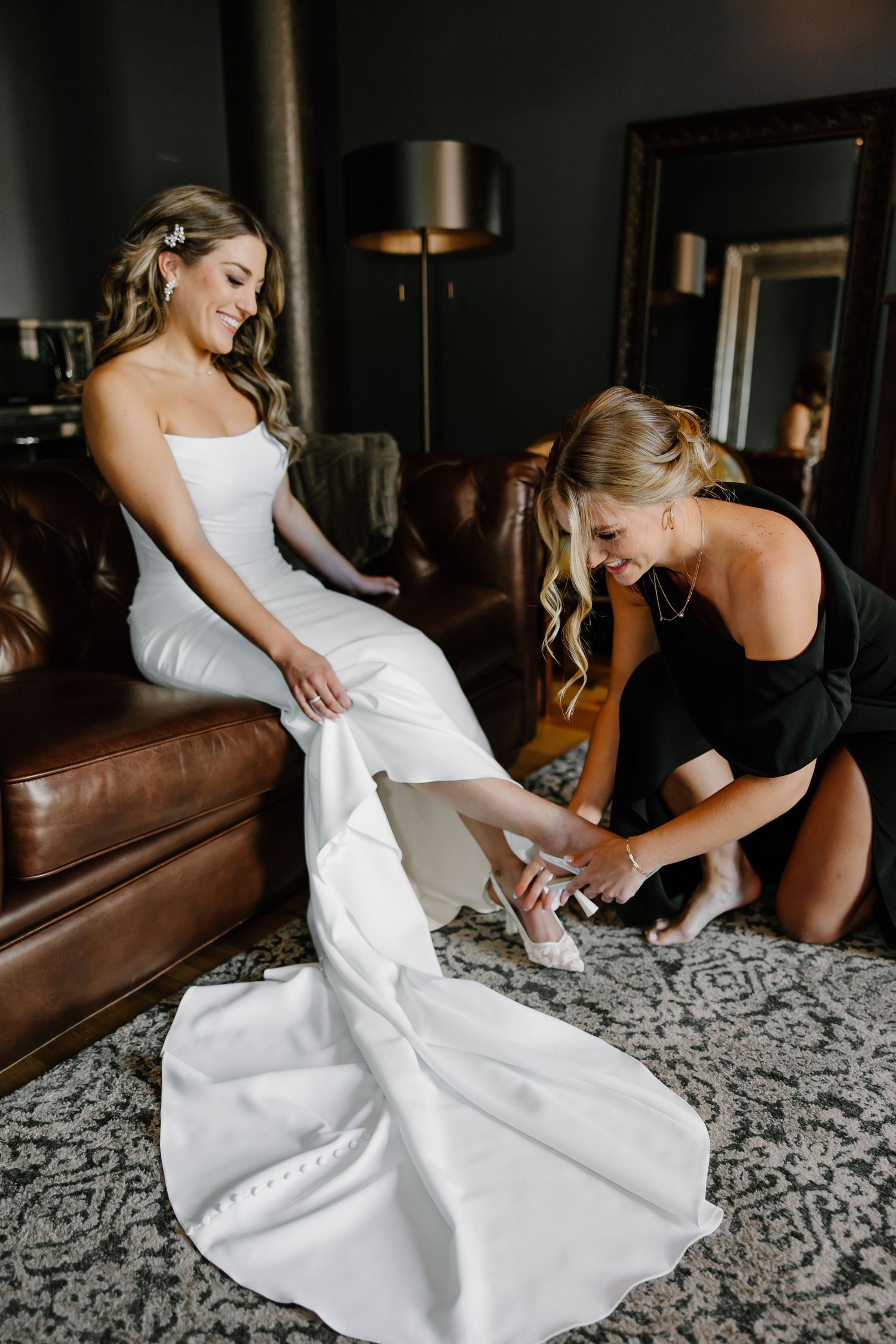 Wedding dress preparation scene on patterned carpet in dark room.