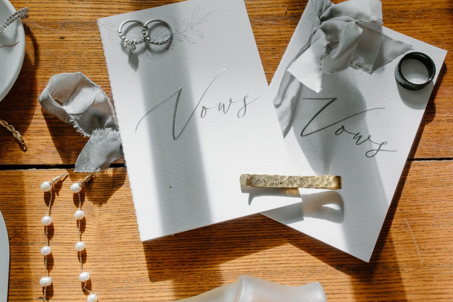 Wedding vows and rings arranged artistically on wooden surface.