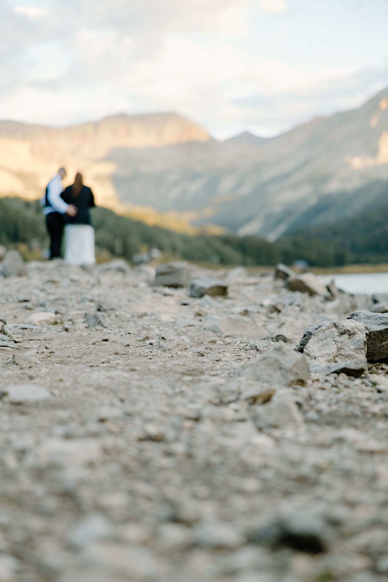 Close-up view of rocky terrain with majestic mountain peaks visible in the soft-focus background.
