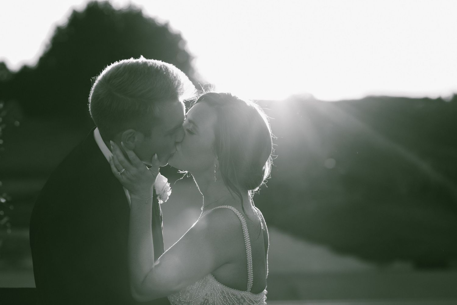 Intimate silhouetted couple against bright sunlit background.
