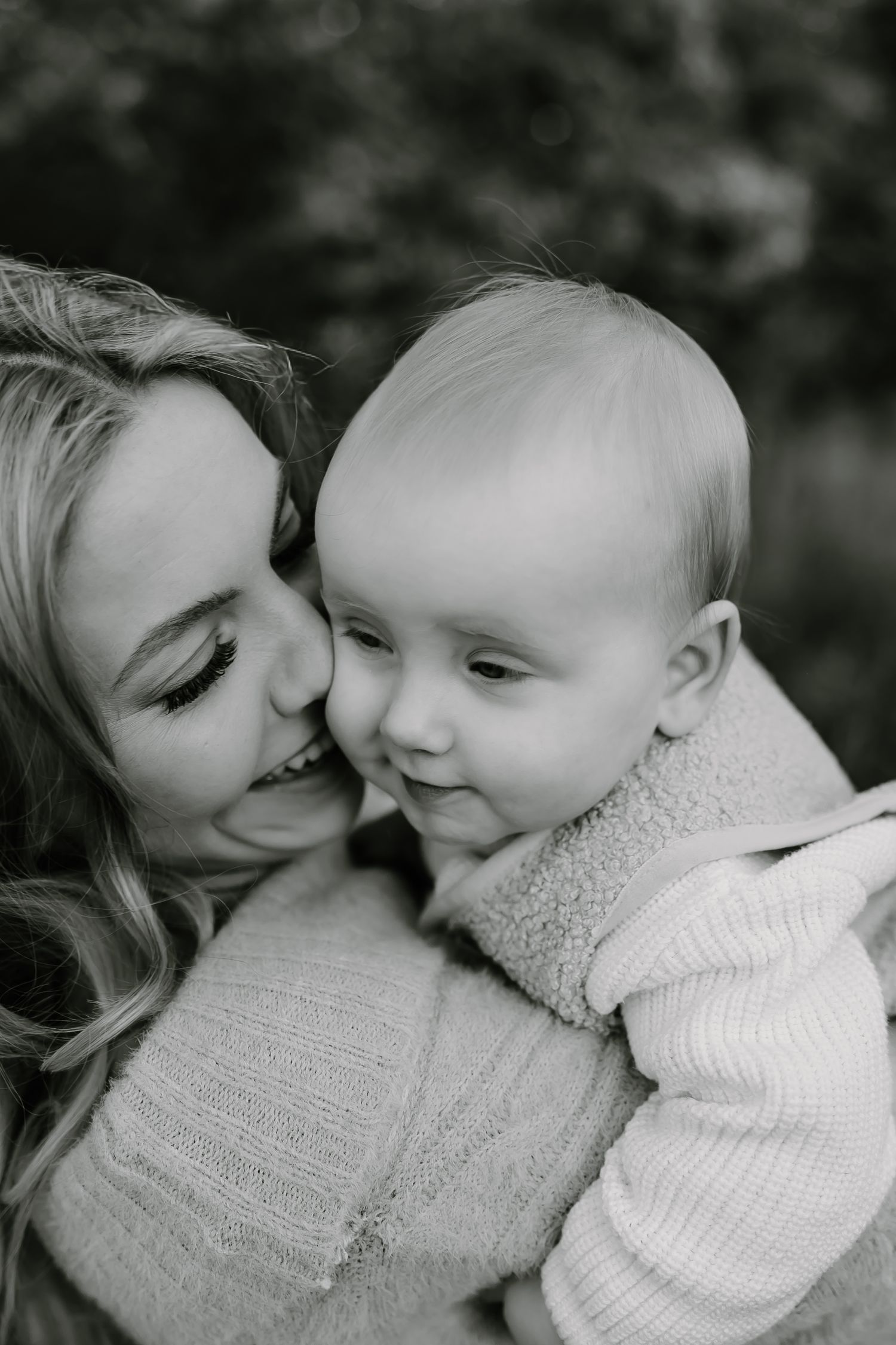 Black and white intimate portrait of parent and baby sharing tender moment.