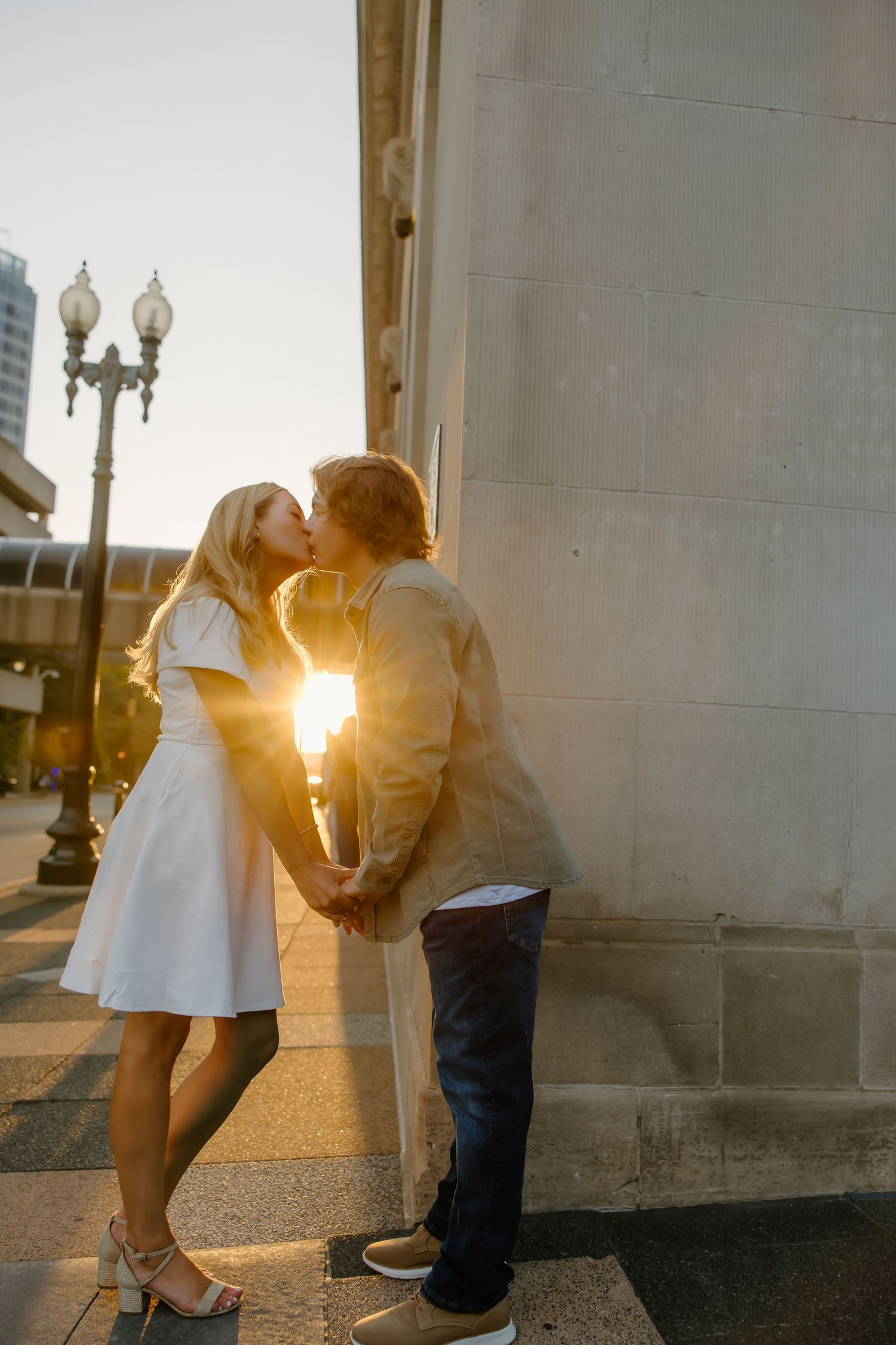 Romantic moments captured against architectural backdrop during golden hour.