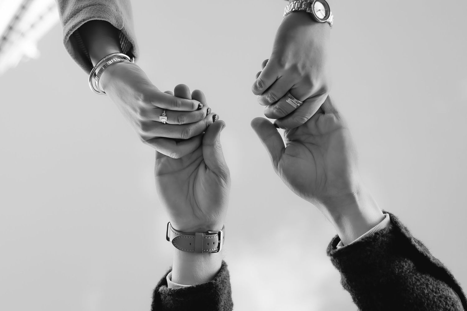 Black and white close-up of two hands reaching towards each other.