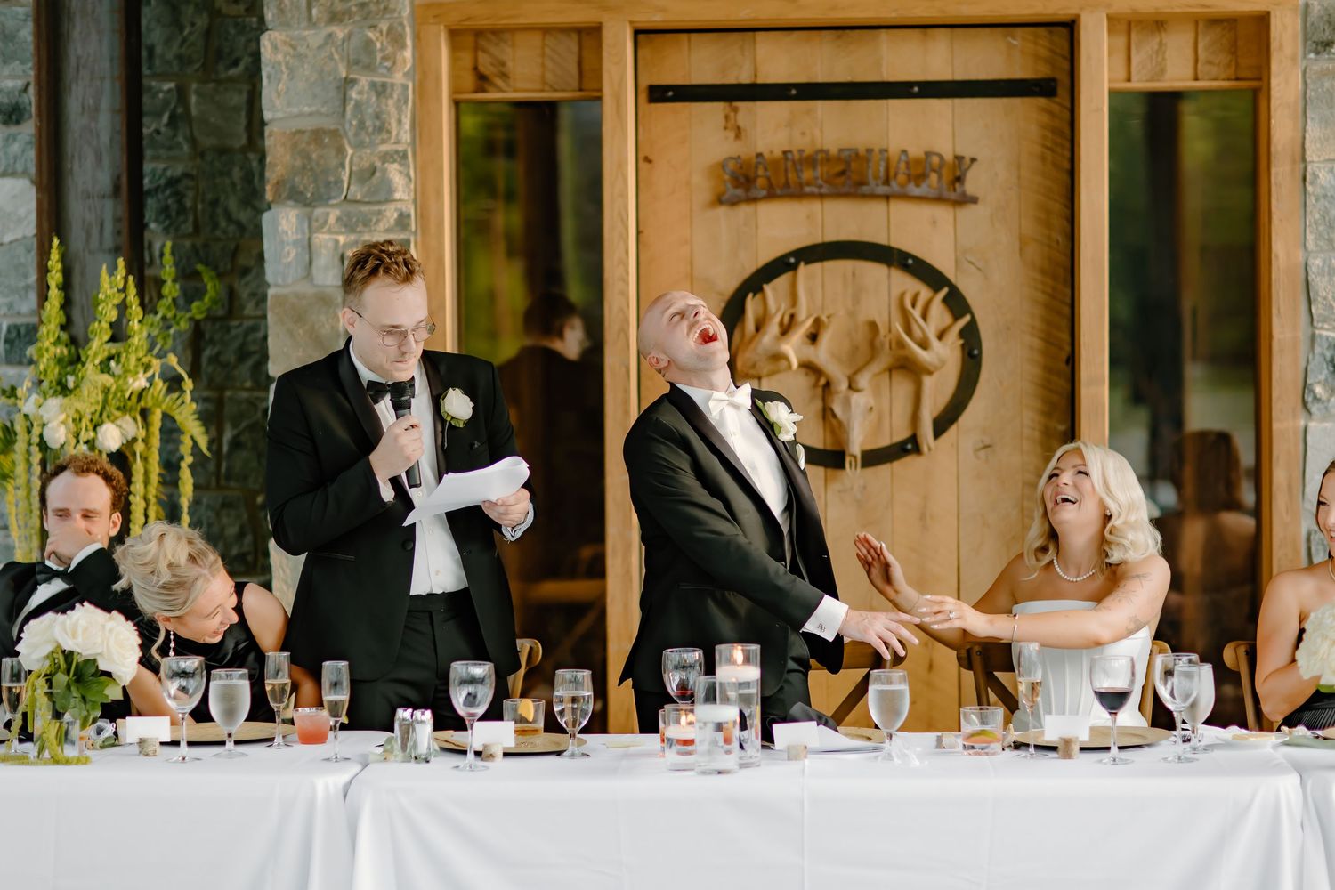 Wedding guests seated at long tables during reception in stone-walled venue.