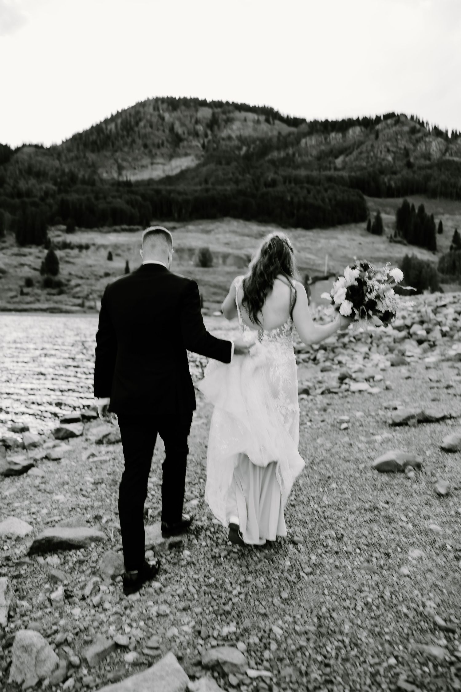 Black and white wedding photography sequence on a rocky mountain lakeshore with dramatic landscape.