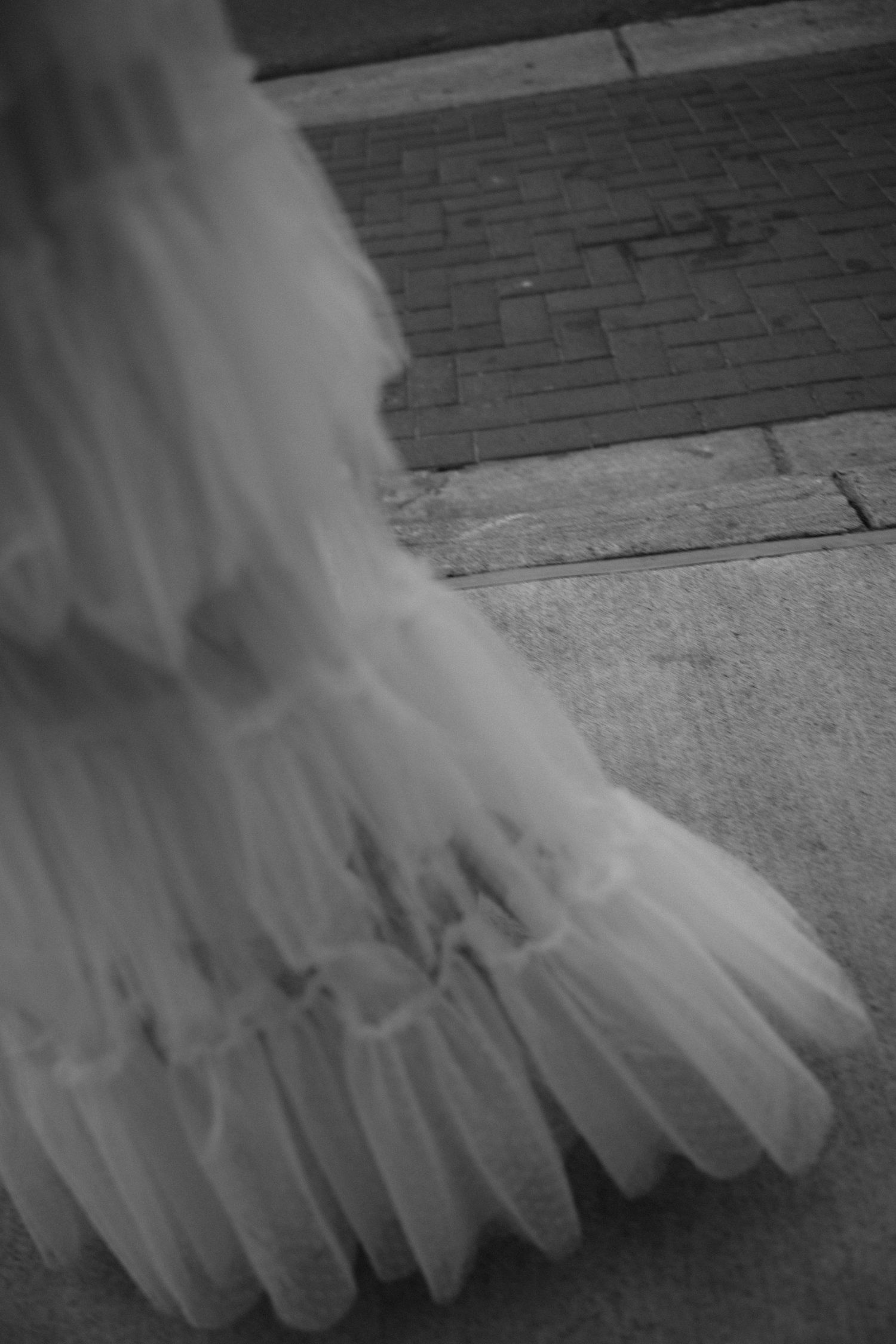 Black and white detail shot of flowing tulle fabric on ground.