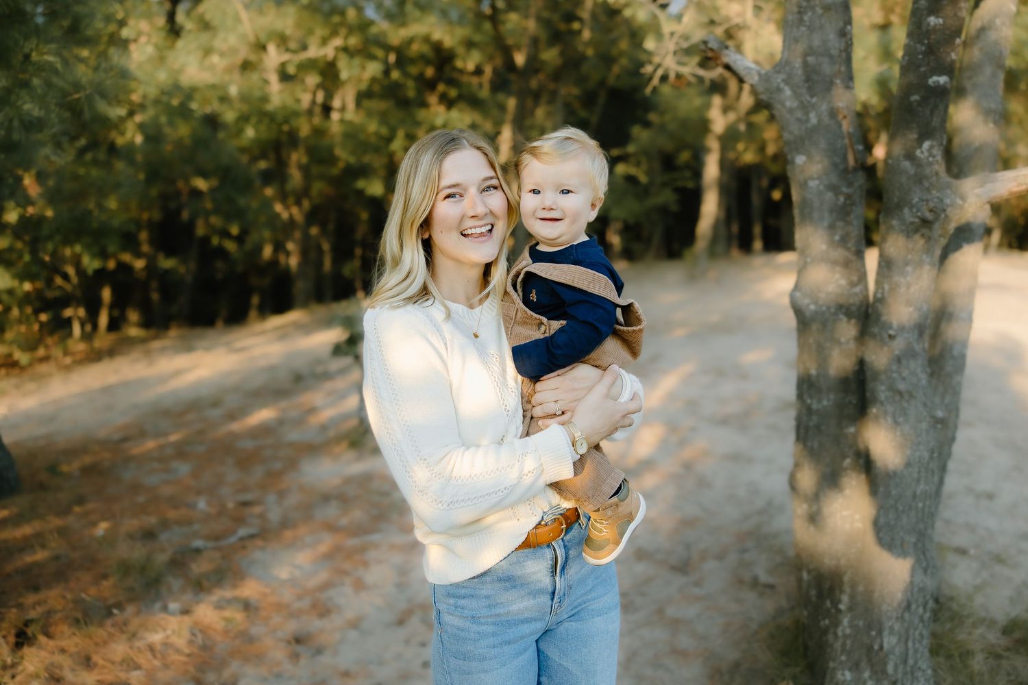 A tender outdoor family portrait session with golden sunlight filtering through trees.