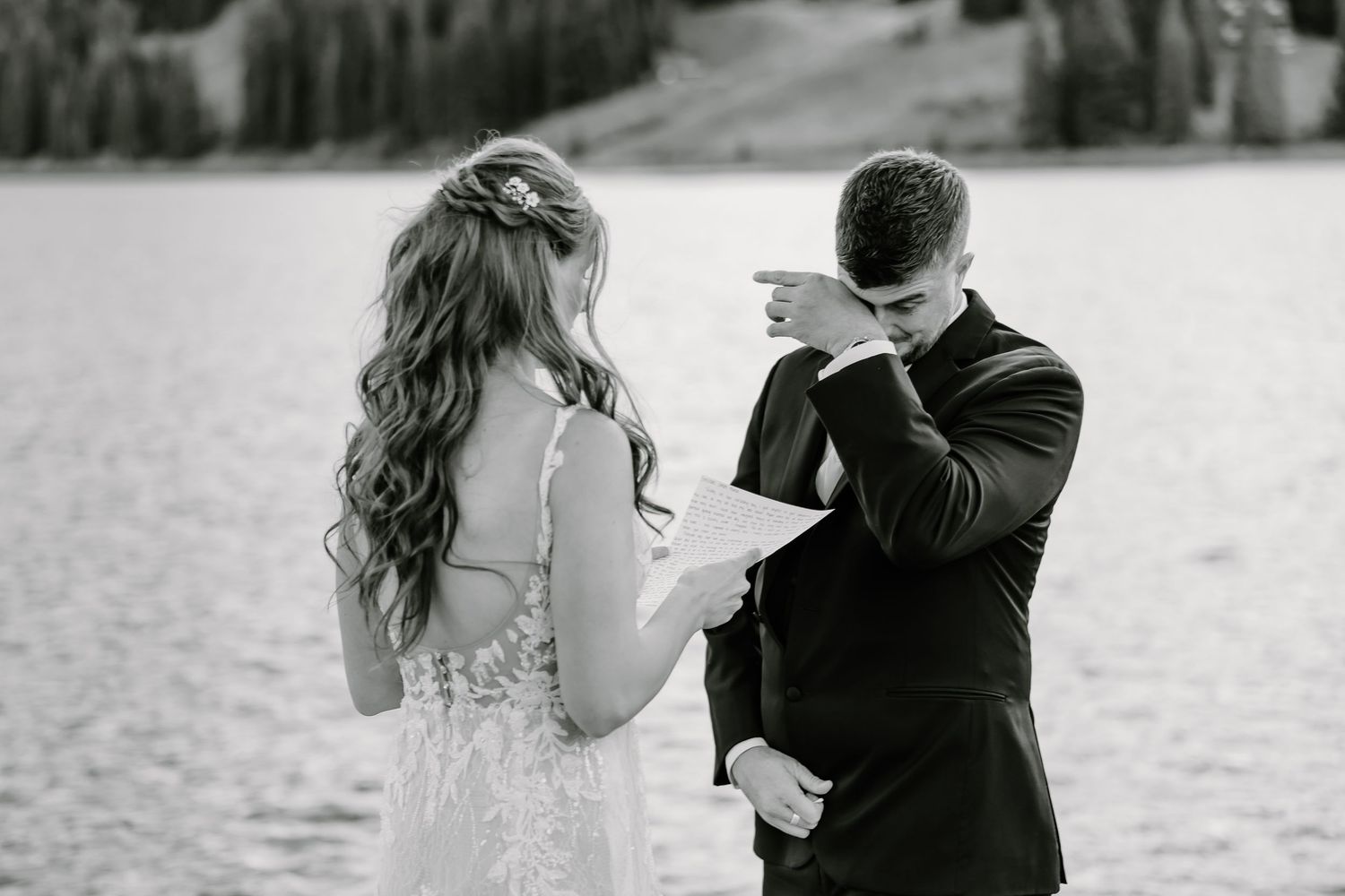 Black and white moment of wedding vows being read beside a mountain lake.