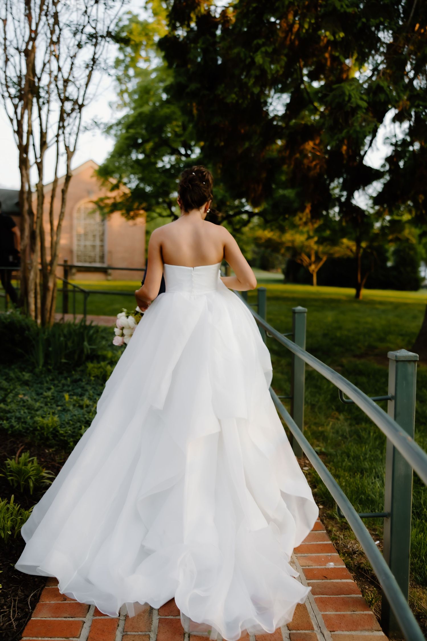 Wedding dress flowing behind couple walking up brick steps.