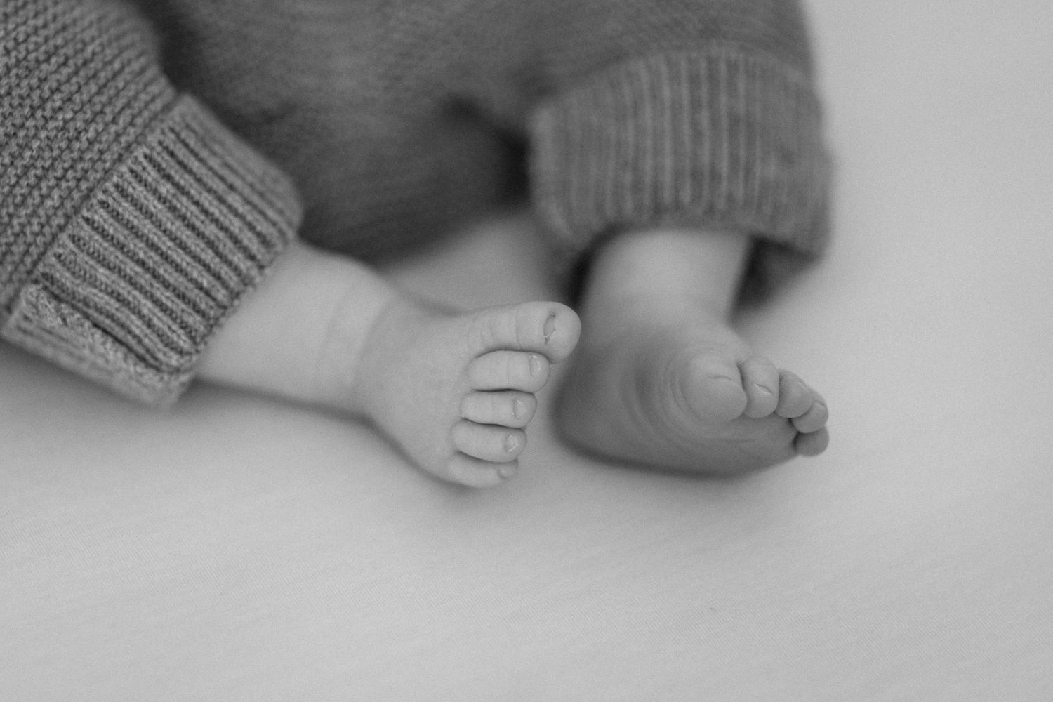 Detail shots of tiny baby feet in gray knit clothing against a light background.
