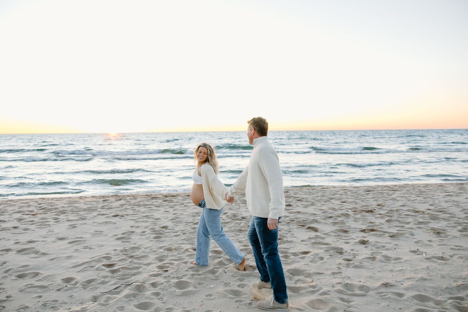 Romantic beach photoshoot with couple walking along the shoreline at dusk.