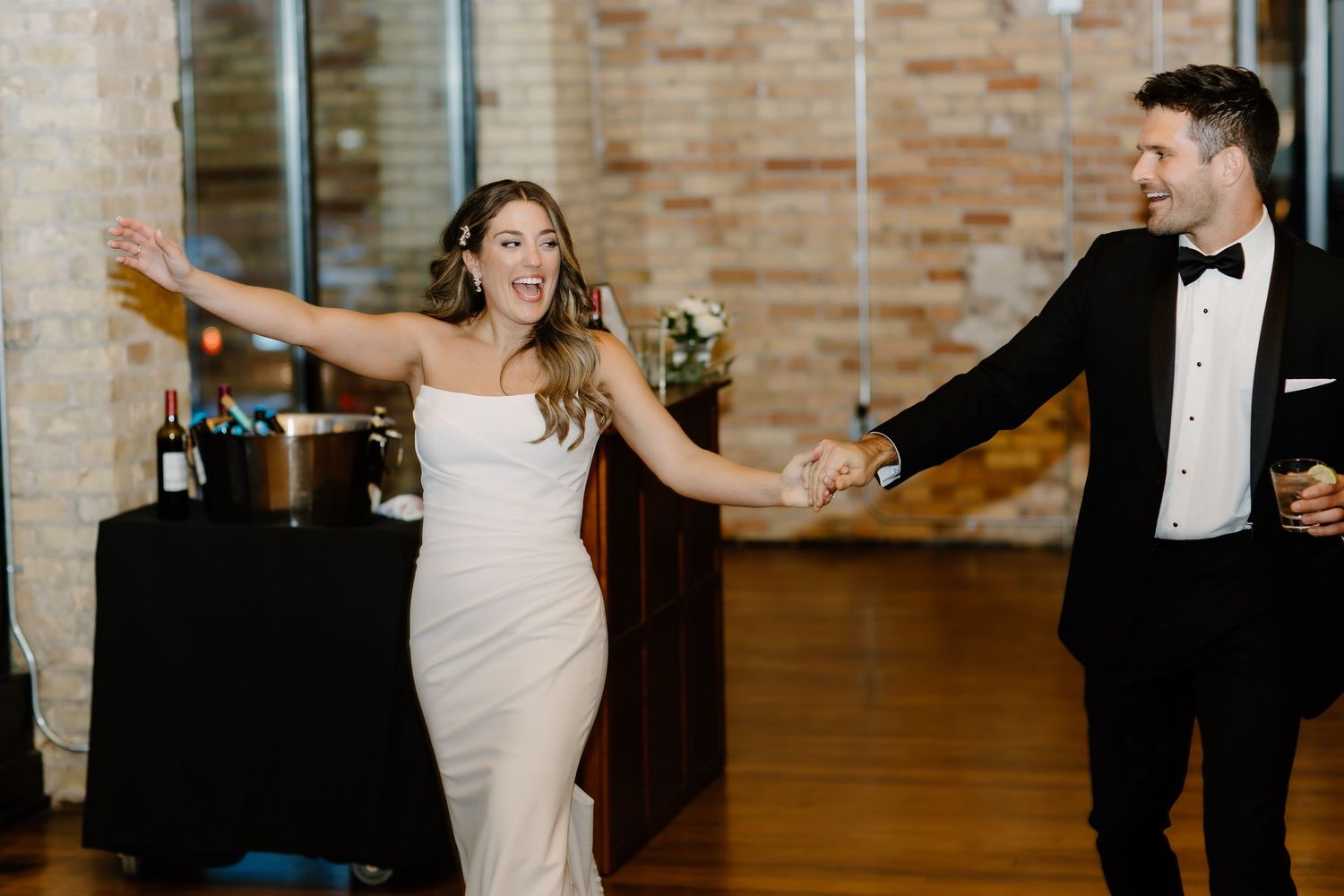 Elegant dance sequence with couple in formal attire against exposed brick wall.