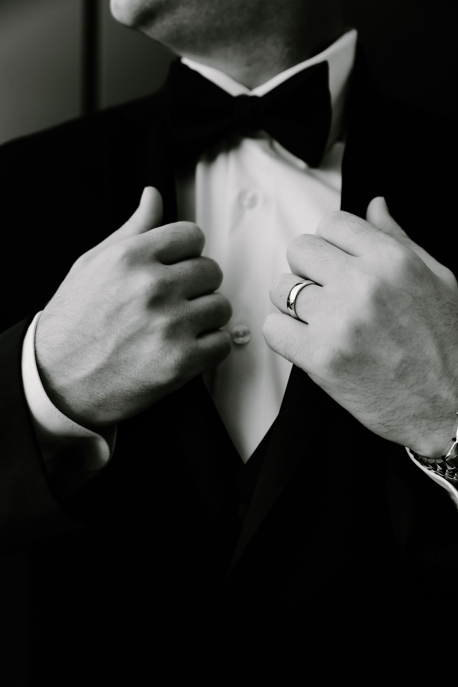Close-up black and white detail of formal attire adjustments.