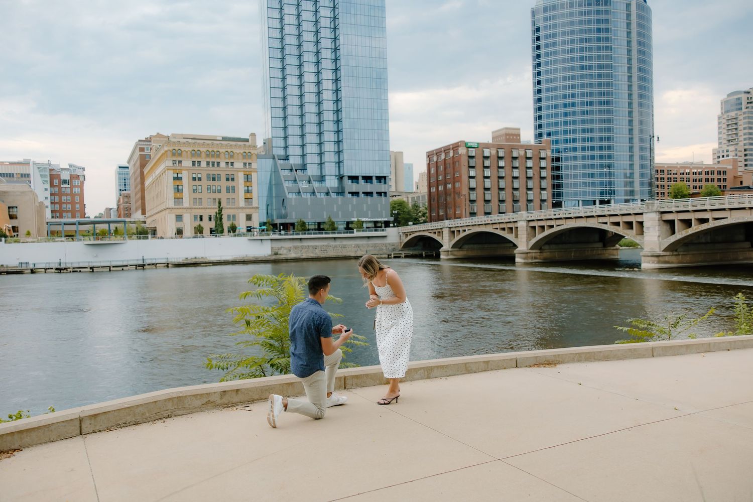 Urban waterfront scene with glass skyscrapers and historic architecture along a river.