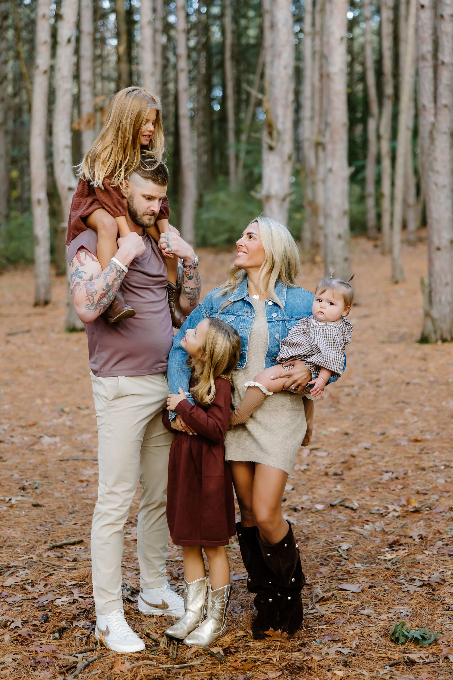 Joyful family interaction during an autumn photoshoot in a wooded setting.