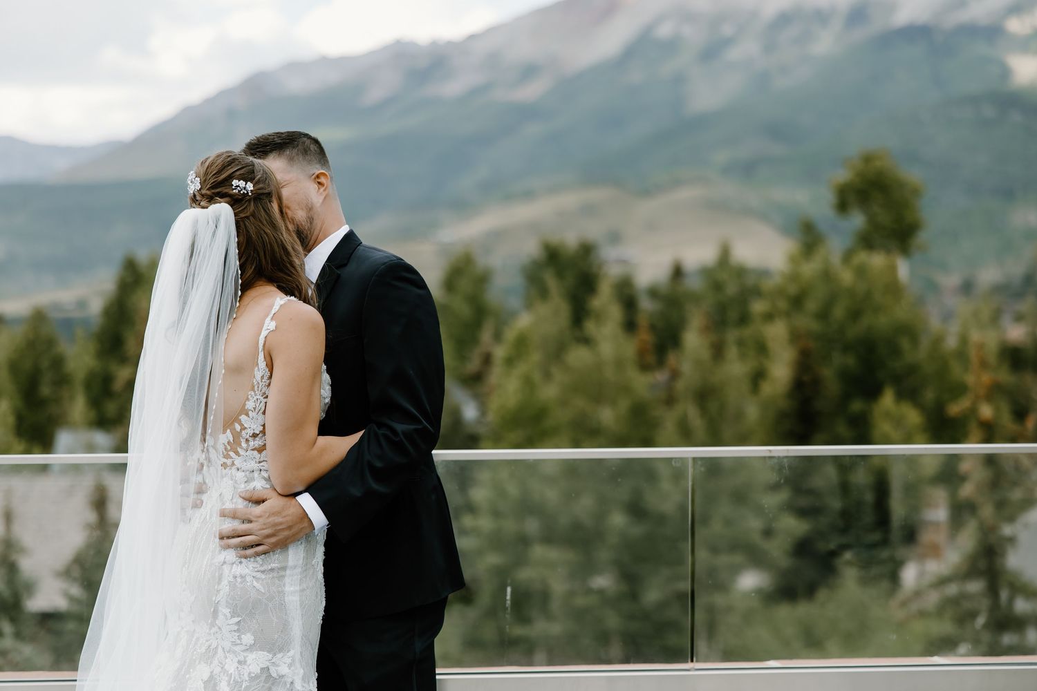 Newlyweds embrace on a scenic mountain deck during their wedding day.