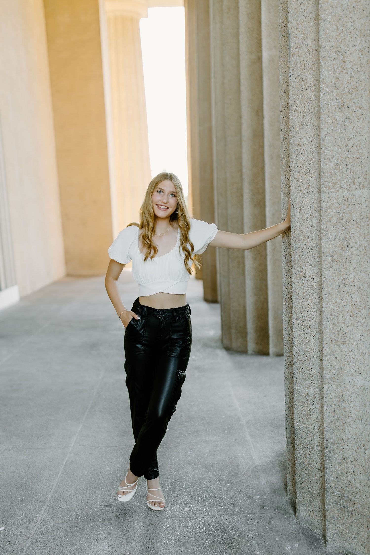 Stylish outfit featuring a white crop top and black pants in an architectural setting with columns.